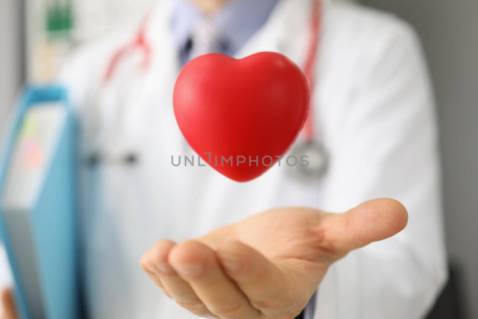 Close-up of cardiologist throw red plastic heart and catch it in palm, save life through donation or charity activity. Medicine, cardiology, health concept