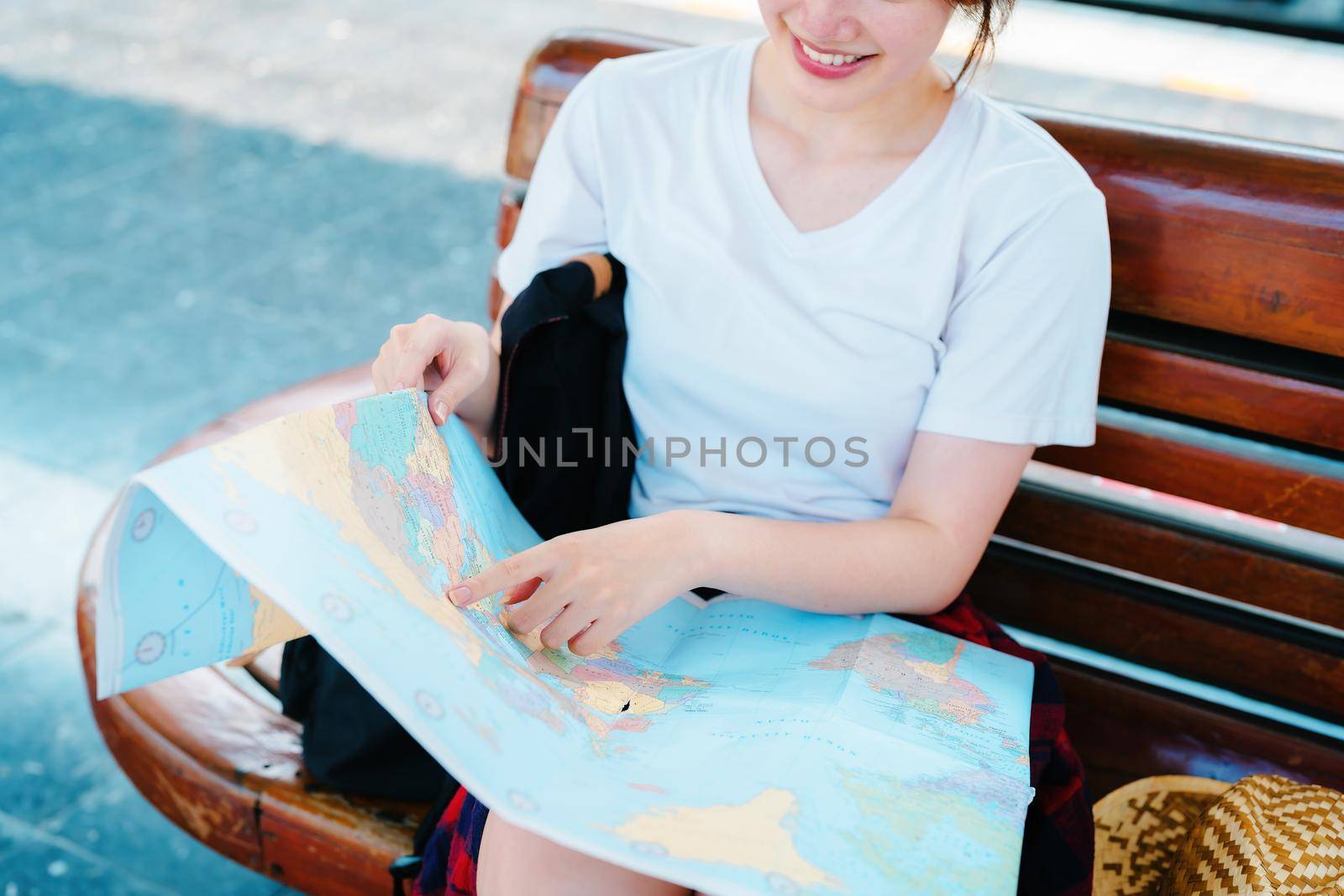 summer, relax, vacation, travel, portrait of a cute Asian girl looking at a map to plan a trip while waiting at the train station