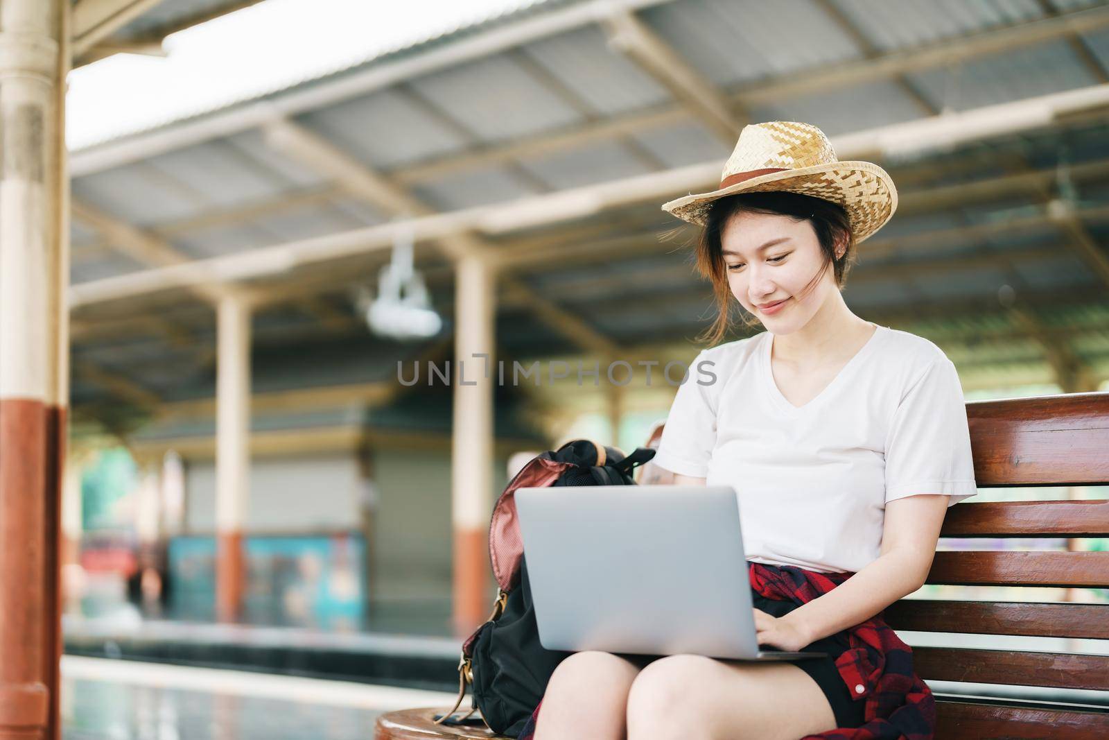 summer, relax, vacation, travel, portrait of beautiful Asian girl using the computer laptop at the train station while waiting for their travel time. by Manastrong