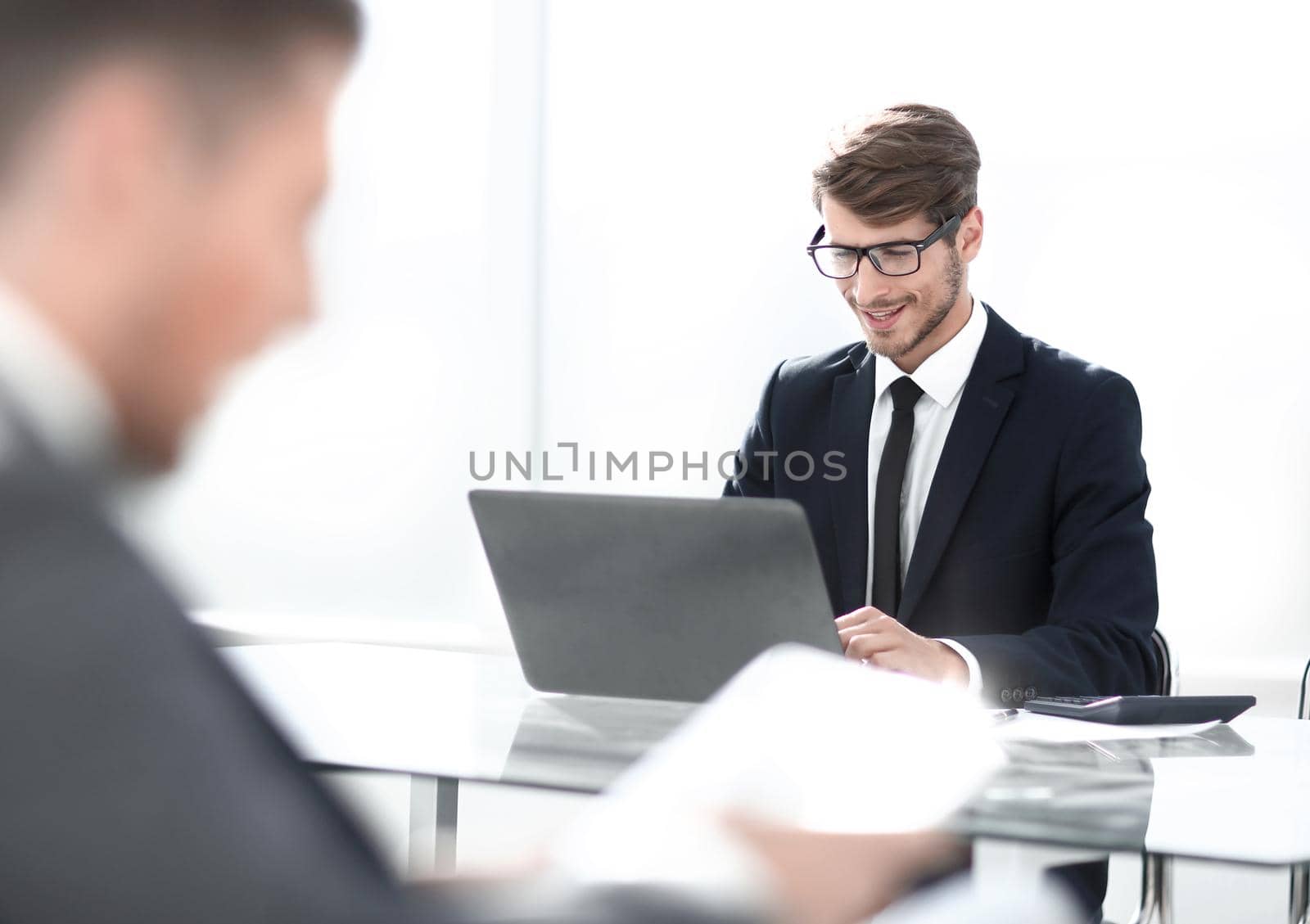 young businessman looking at computer, his colleague using tablet