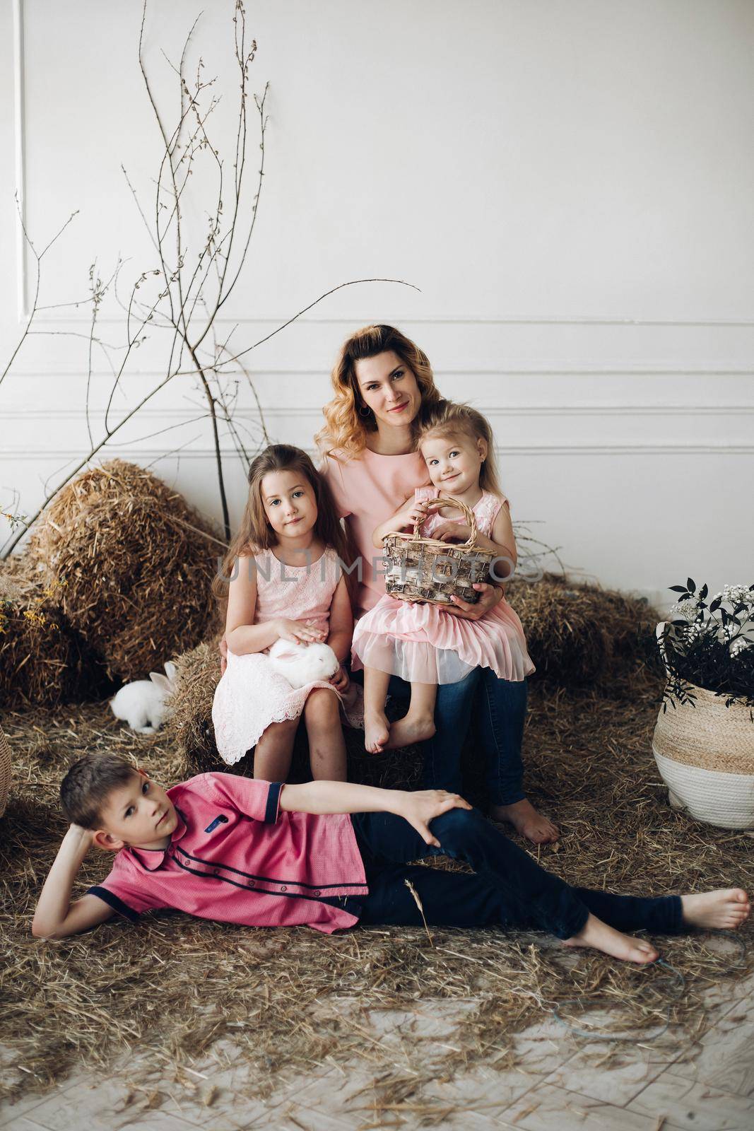 Portrait of cute family looking at camera and smiling at home. Young attractive mother posing with son and cute daughters. Lovely family hugging each other. Concept of love and motherhood.