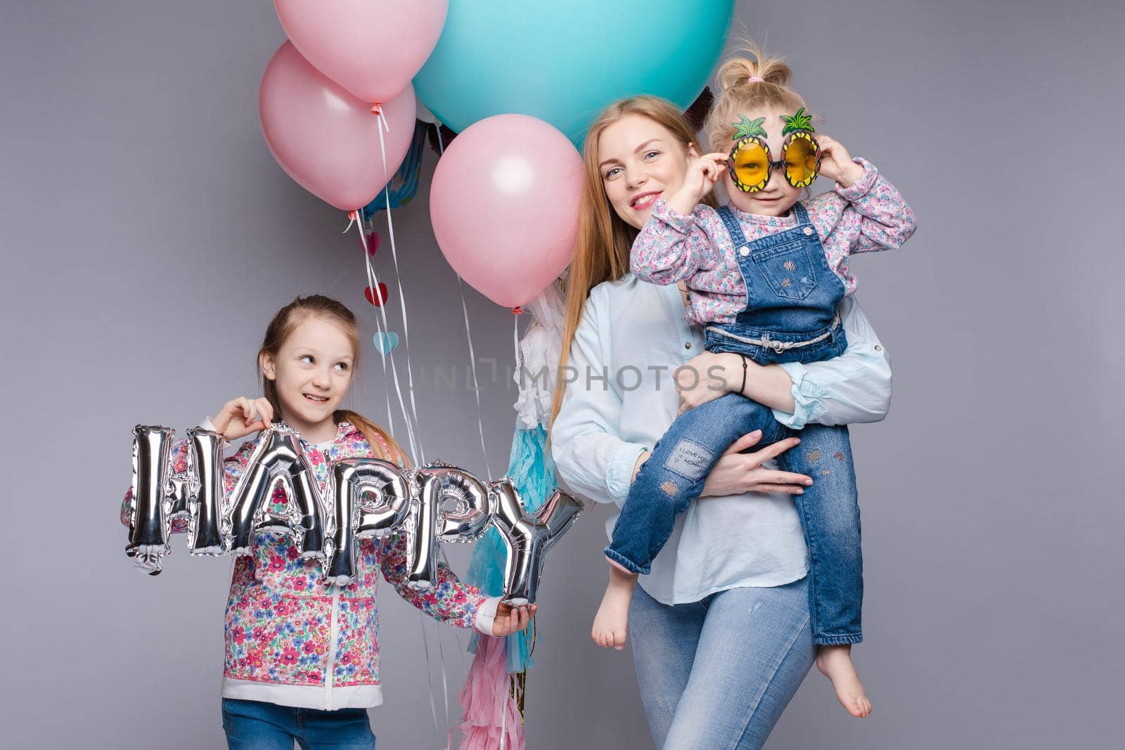 the child in the arms of his mother on a white background. A woman with a child in her arms holding festive balloons
