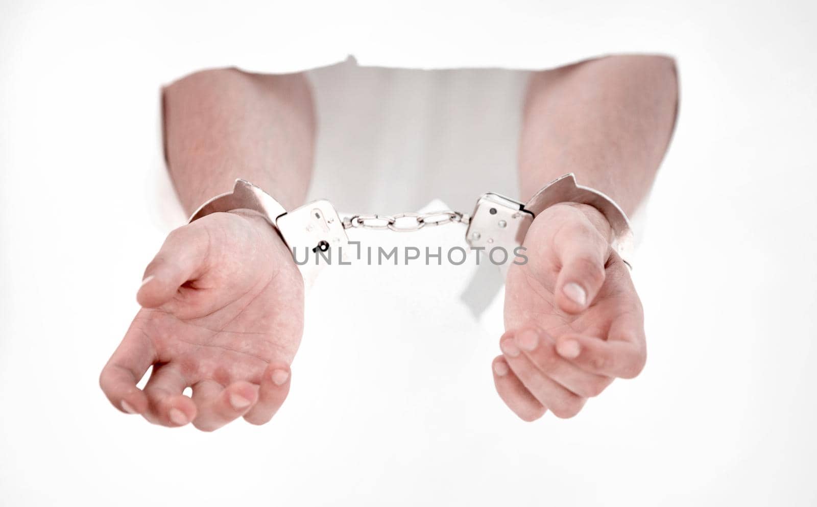 Handcuffs on the hands of a man breaking a paper wall by asdf