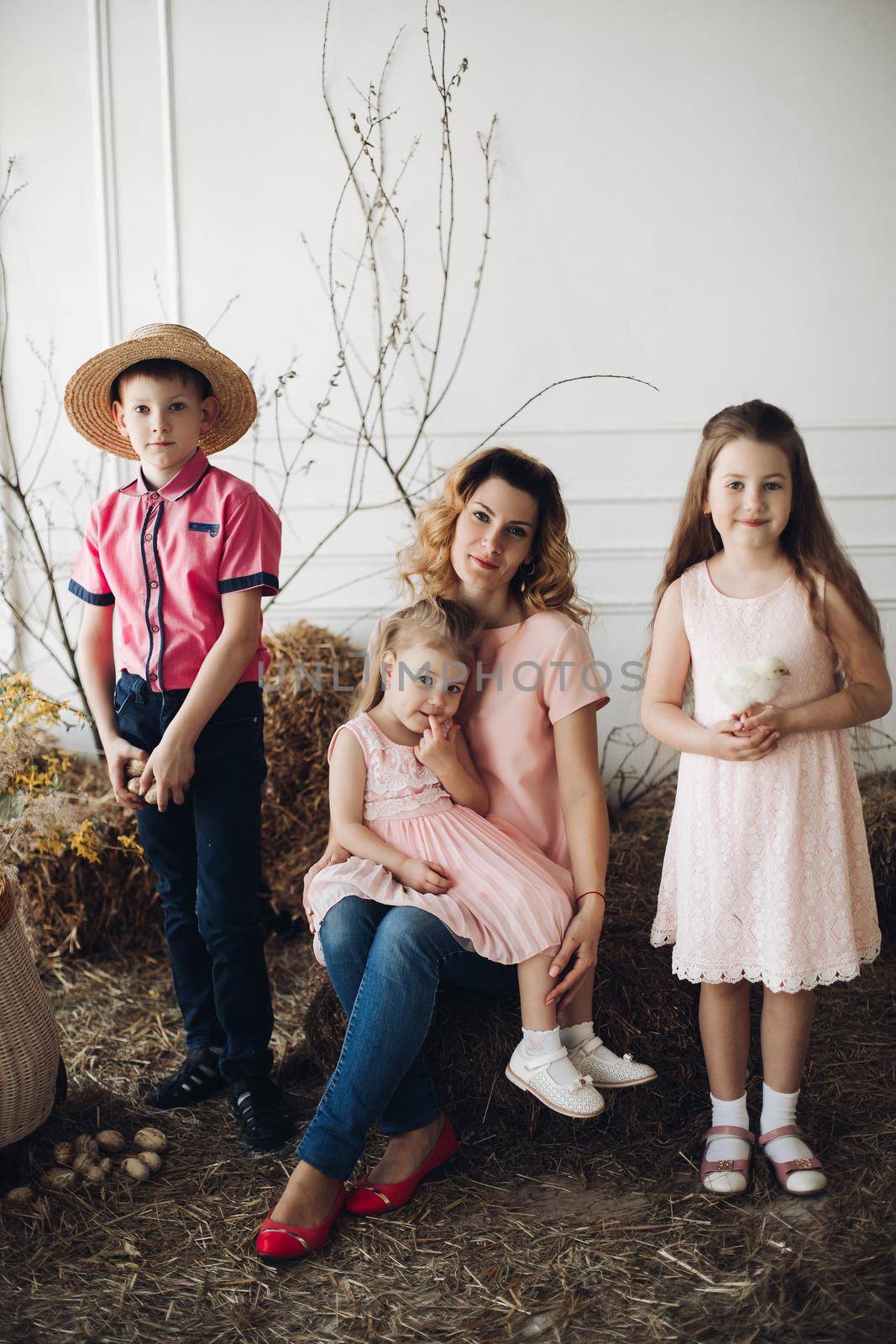 Portrait of cute family looking at camera and smiling at home. Young attractive mother posing with son and cute daughters. Lovely family hugging each other. Concept of love and motherhood.