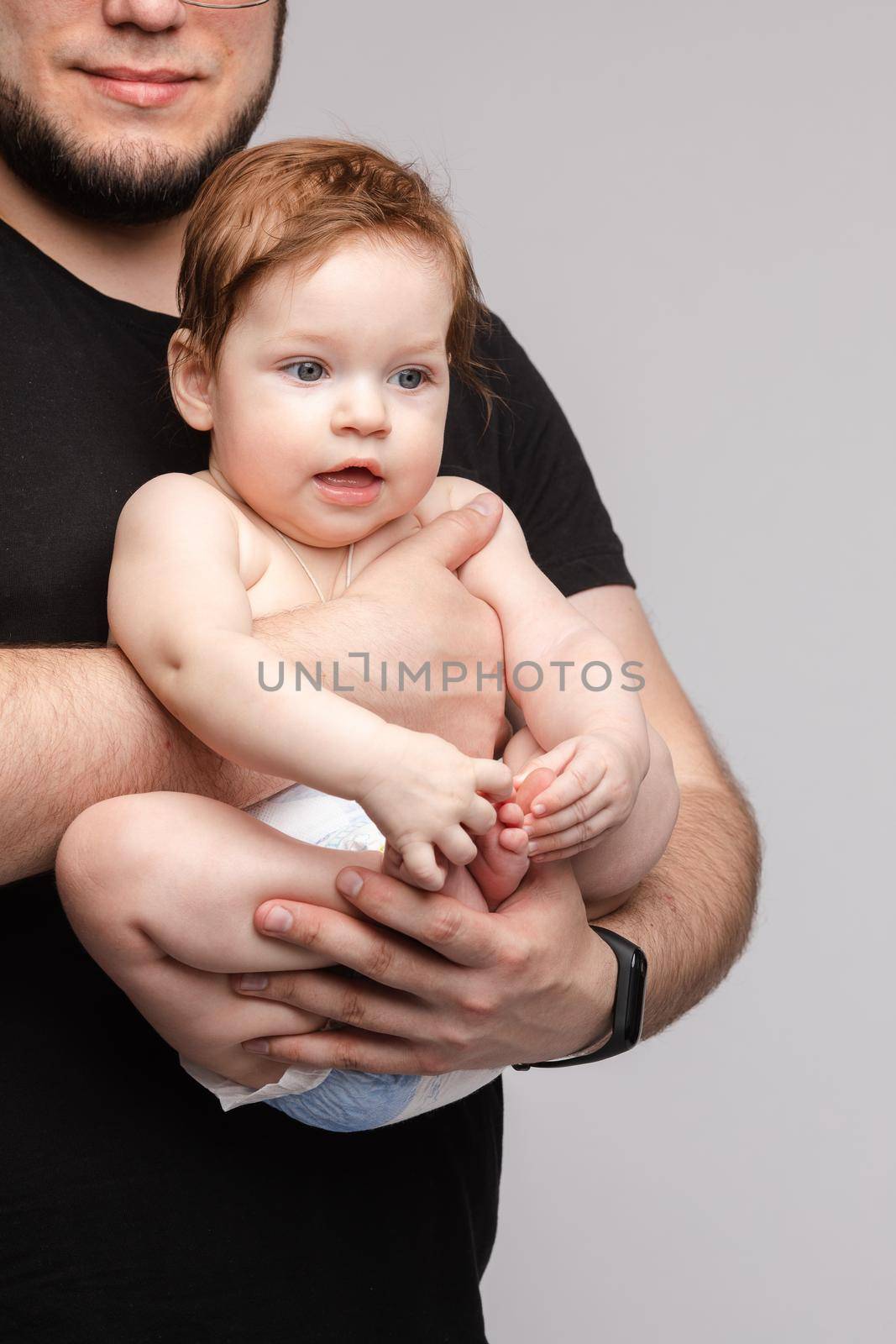 Father keeping little baby in hands and kissing kid by StudioLucky