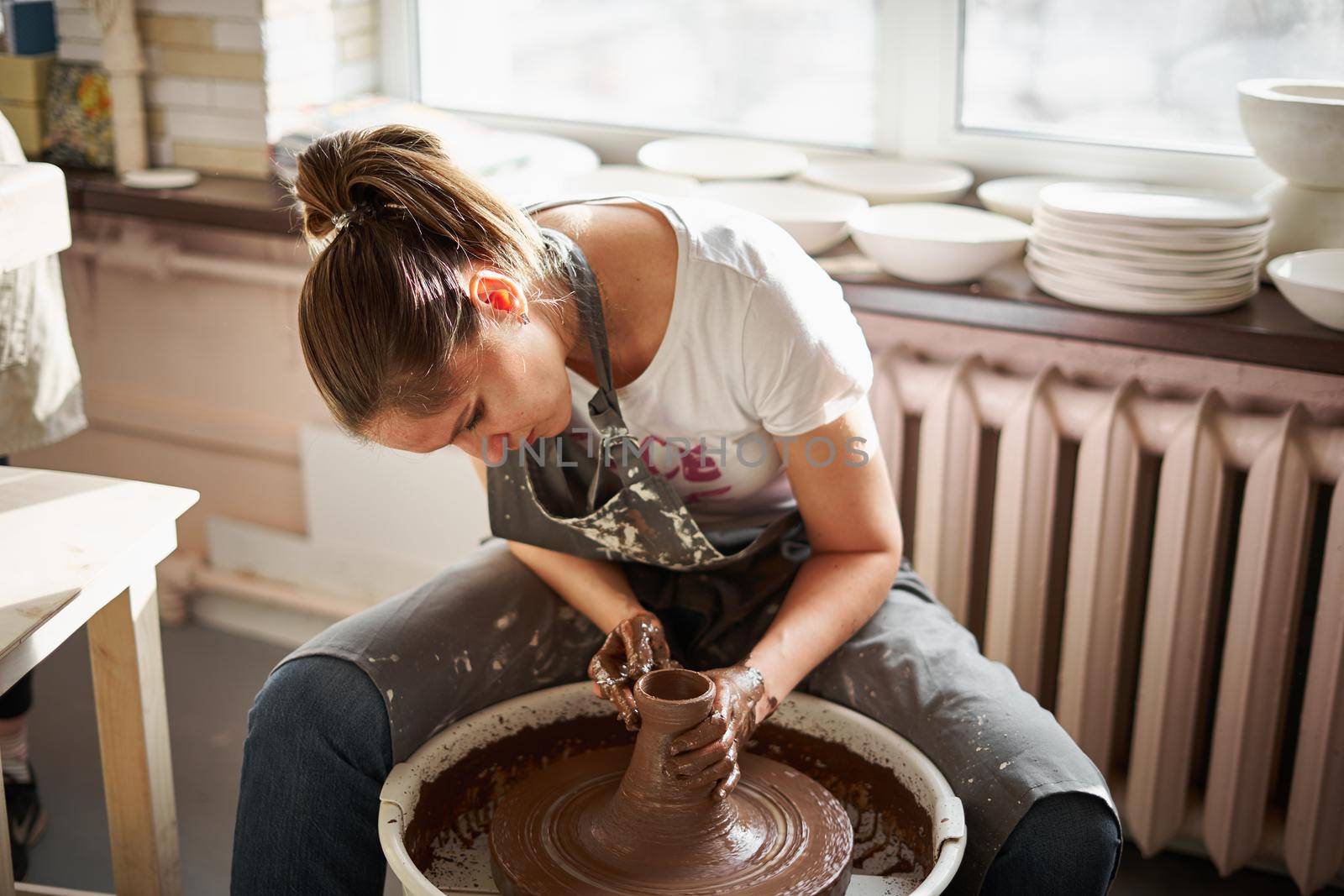 Beautiful woman making ceramic pottery on wheel, hands close-up. Concept for woman in freelance, business, hobby