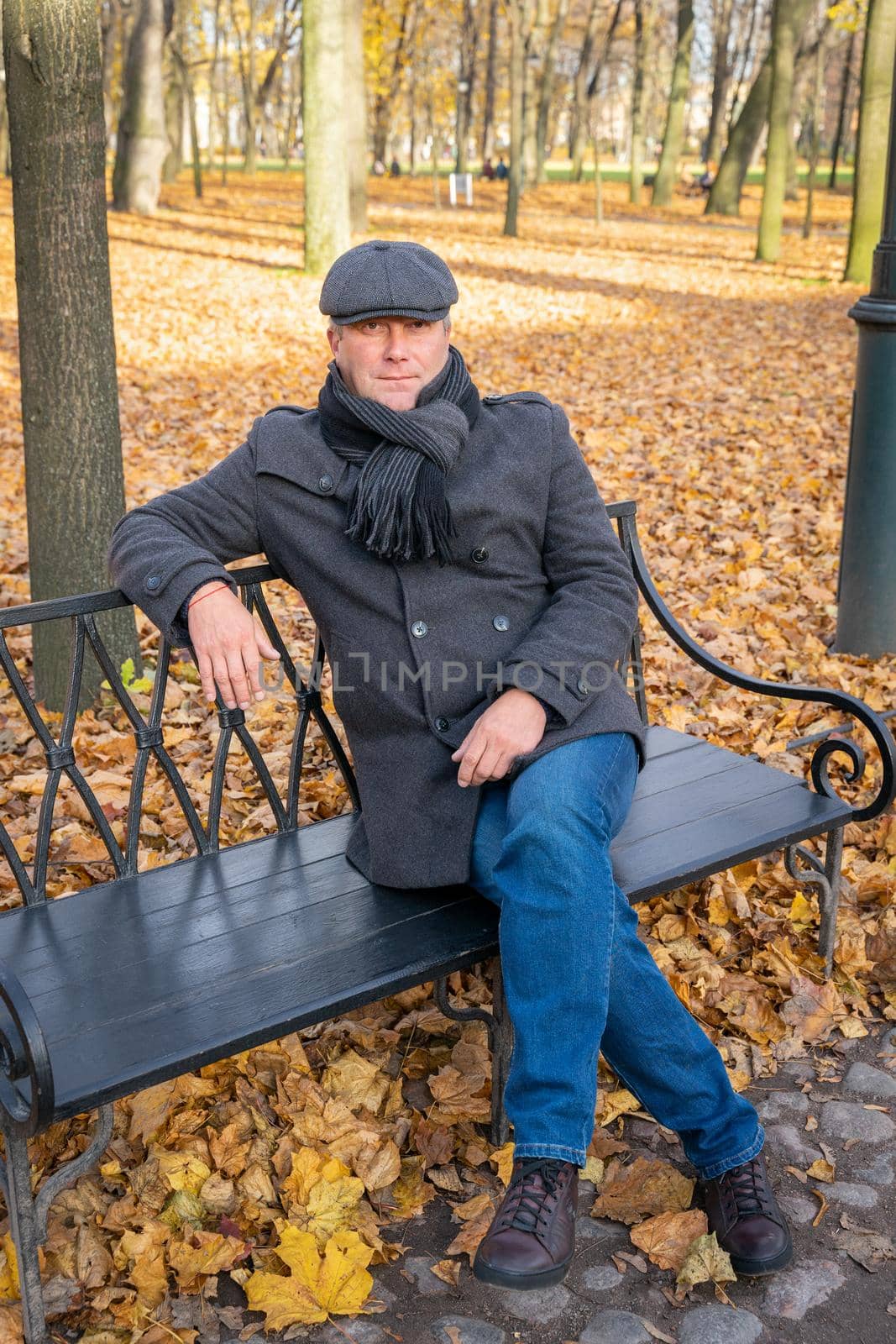 Closeup portrait of a handsome middle-aged full-length brunette man. A mature handsome man of 45-50 years walks in an autumn park in warm clothes, in a coat and cap