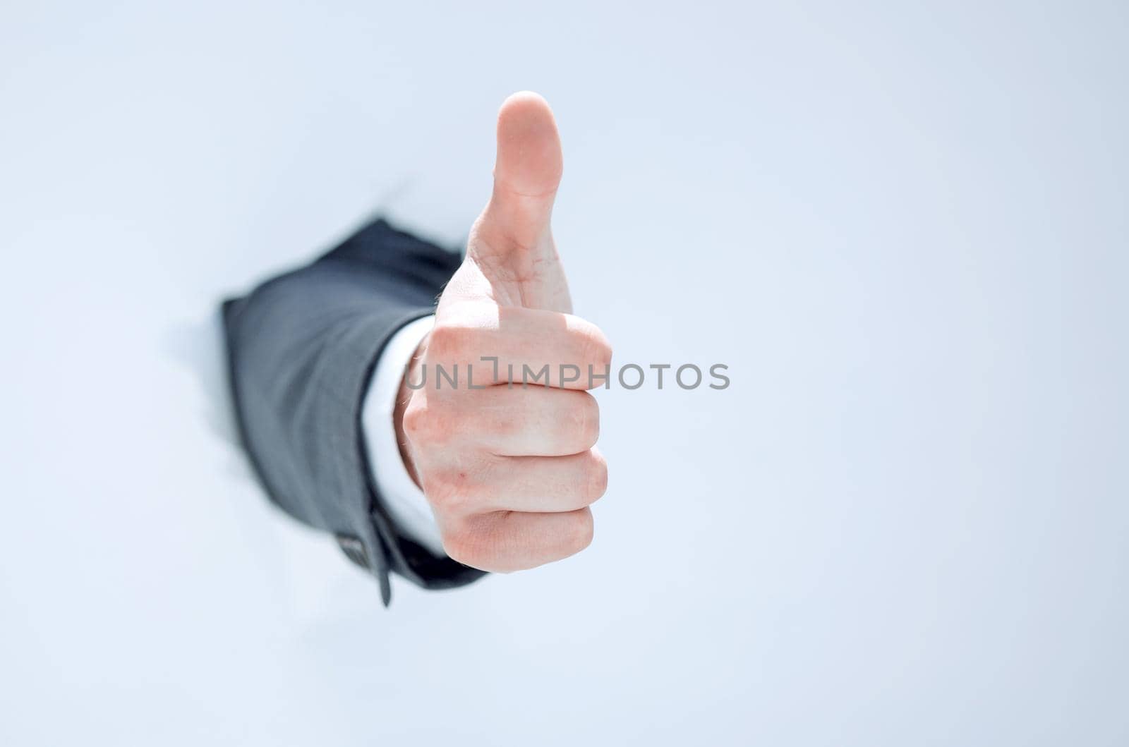 businessman breaks through the paper and shows his thumb up by asdf