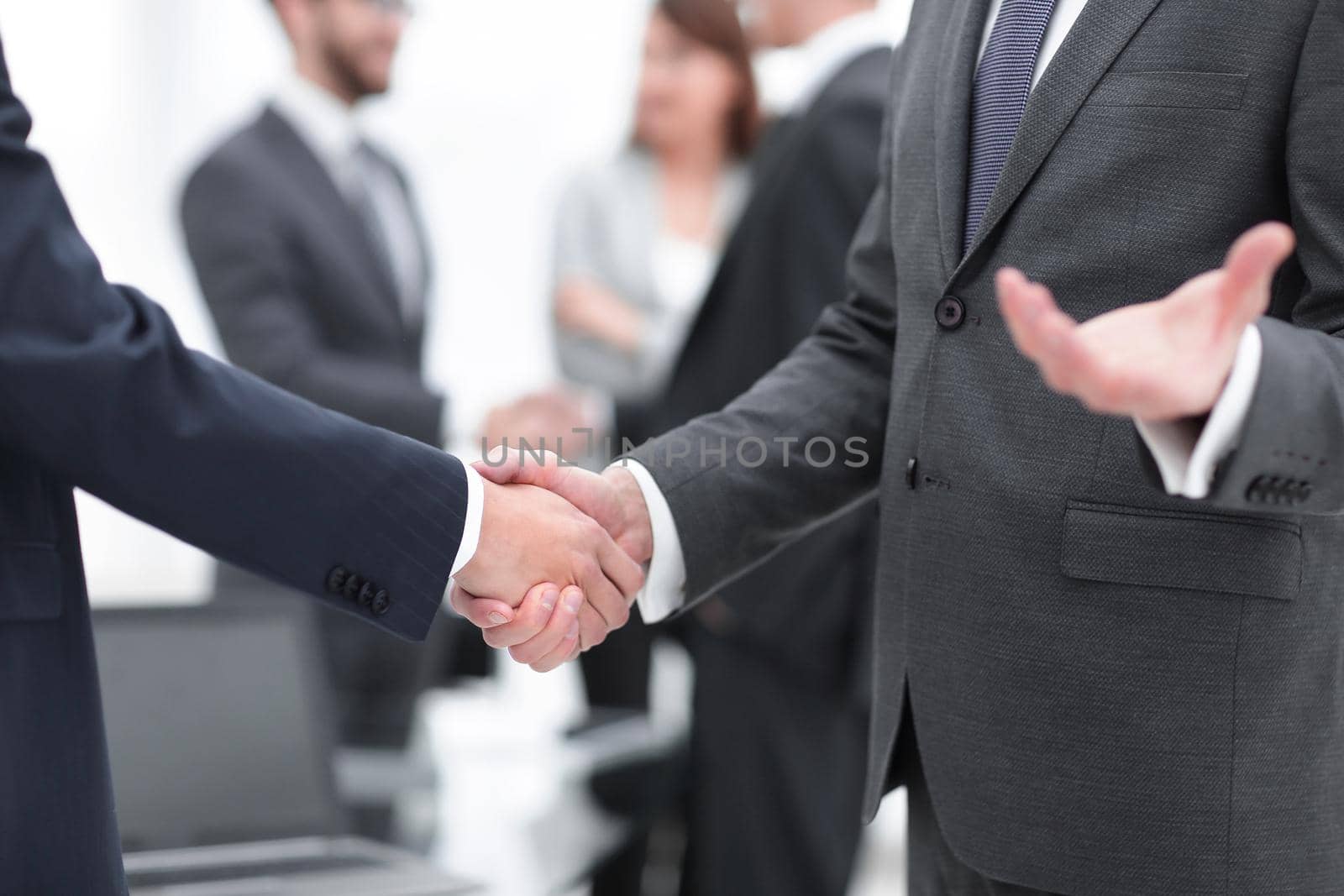 Business partners handshaking over business objects on workplace by asdf