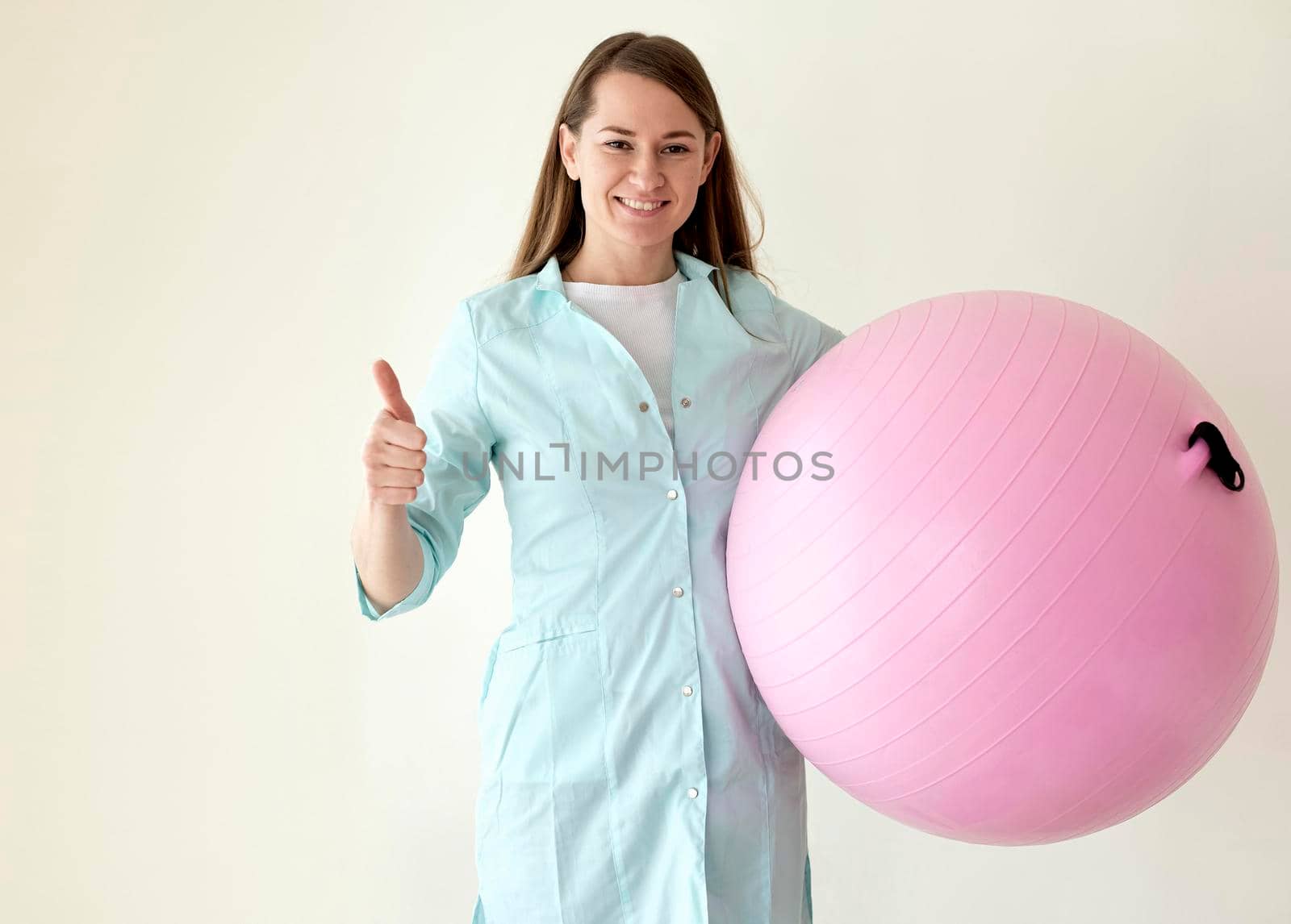 smiley physiotherapist holding exercise ball giving thumbs up by Zahard