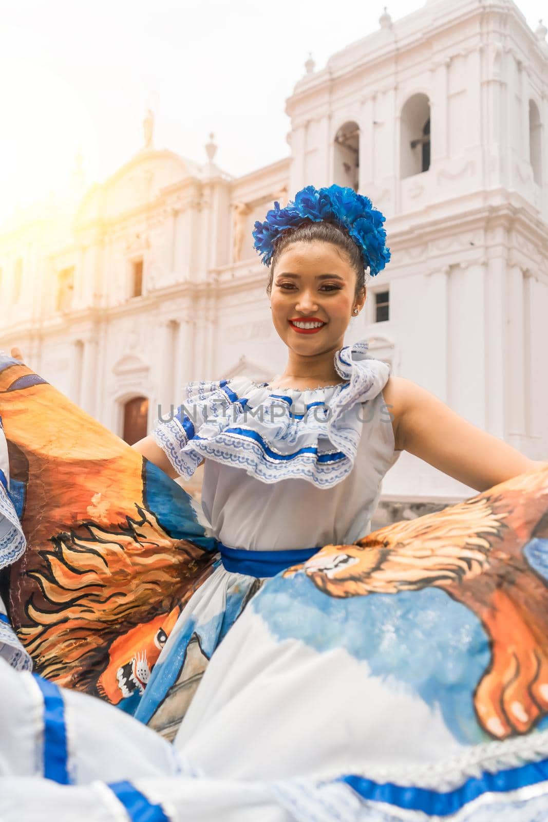 Vertical photo of a Nicaraguan folklore dancer smiling and looking at the camera outside the cathedral church in the central park of the city of Leon. The woman wears the typical dress of Central America and similar to countries of South America and Mexico.