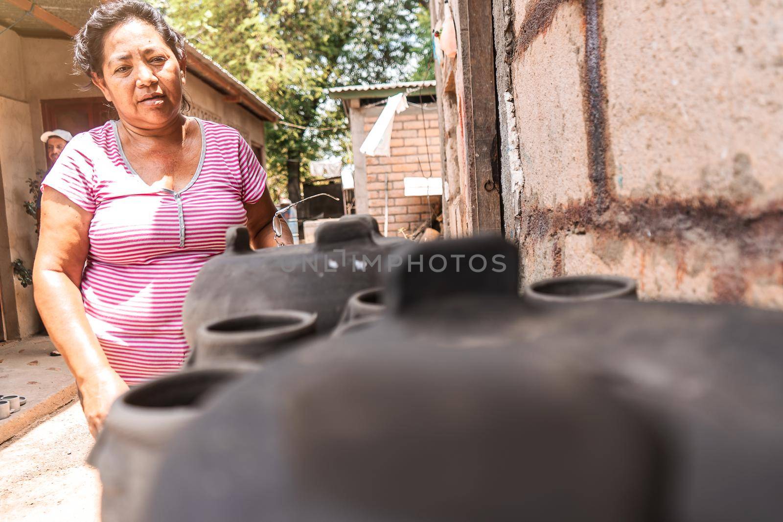 Artisan checking clay pots drying in the sun in a craft workshop in La Paz Centro, Nicaragua. Concept of travel, culture and economy in poor countries by cfalvarez