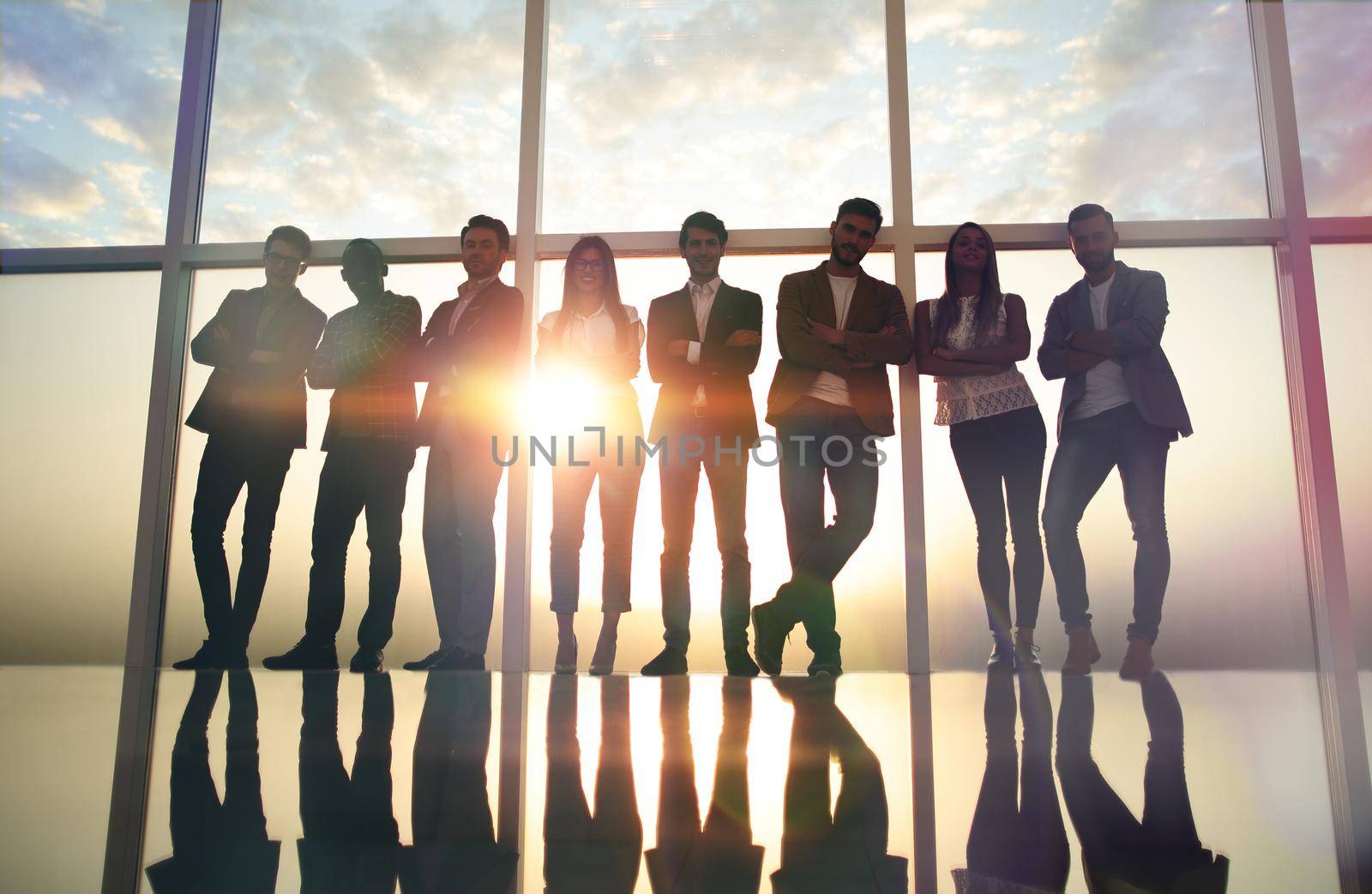 group of young professionals standing in an office with a large window. the concept of employment