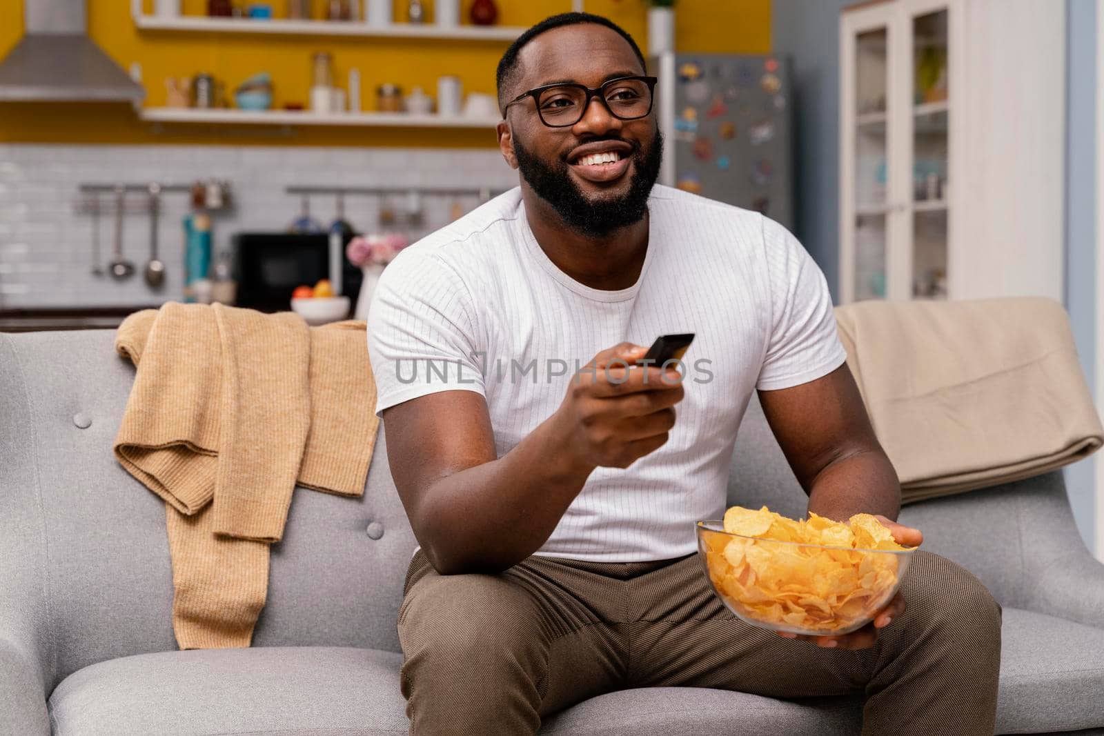 man watching tv eating chips