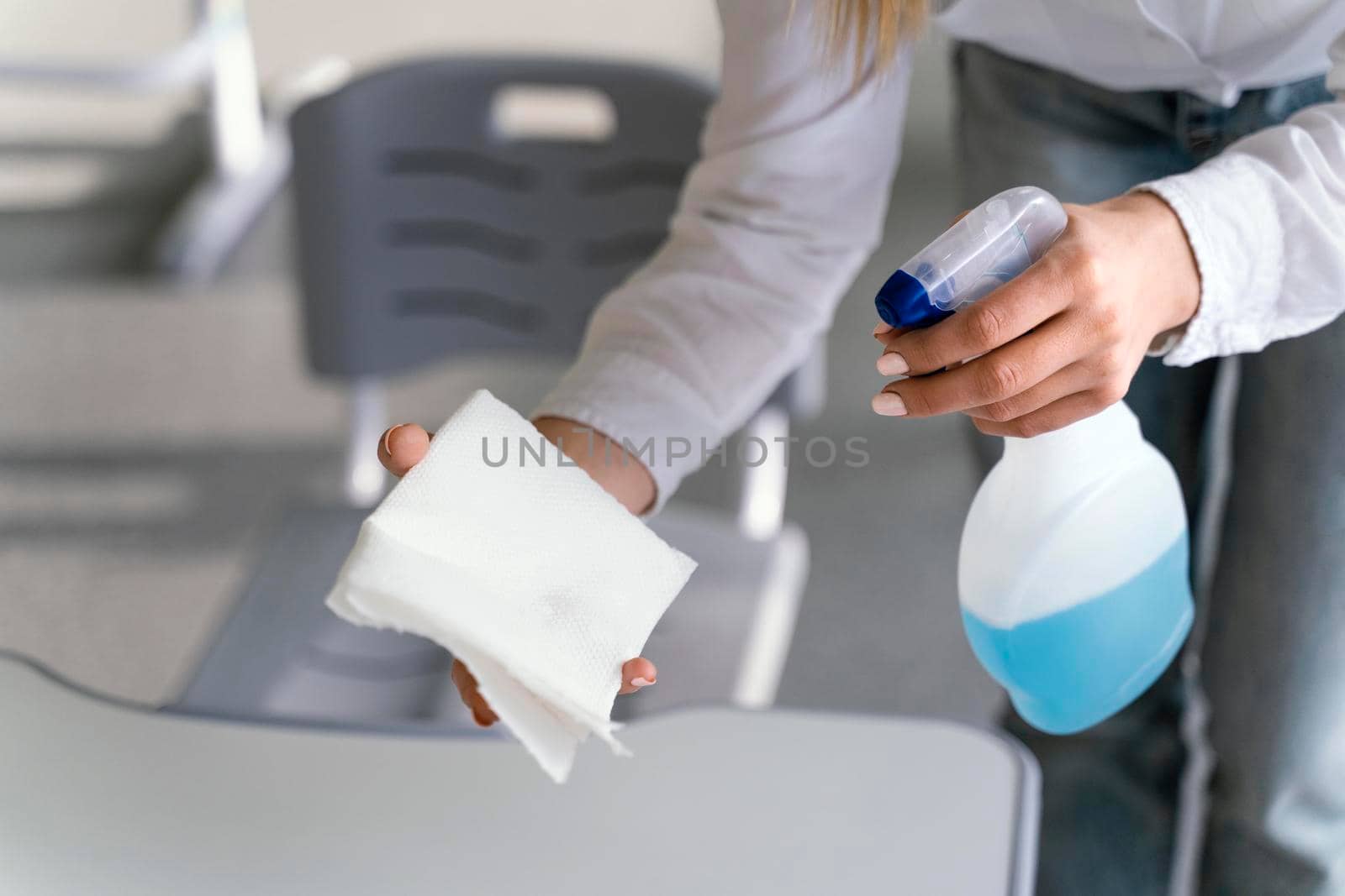 high angle teacher disinfecting school benches classroom