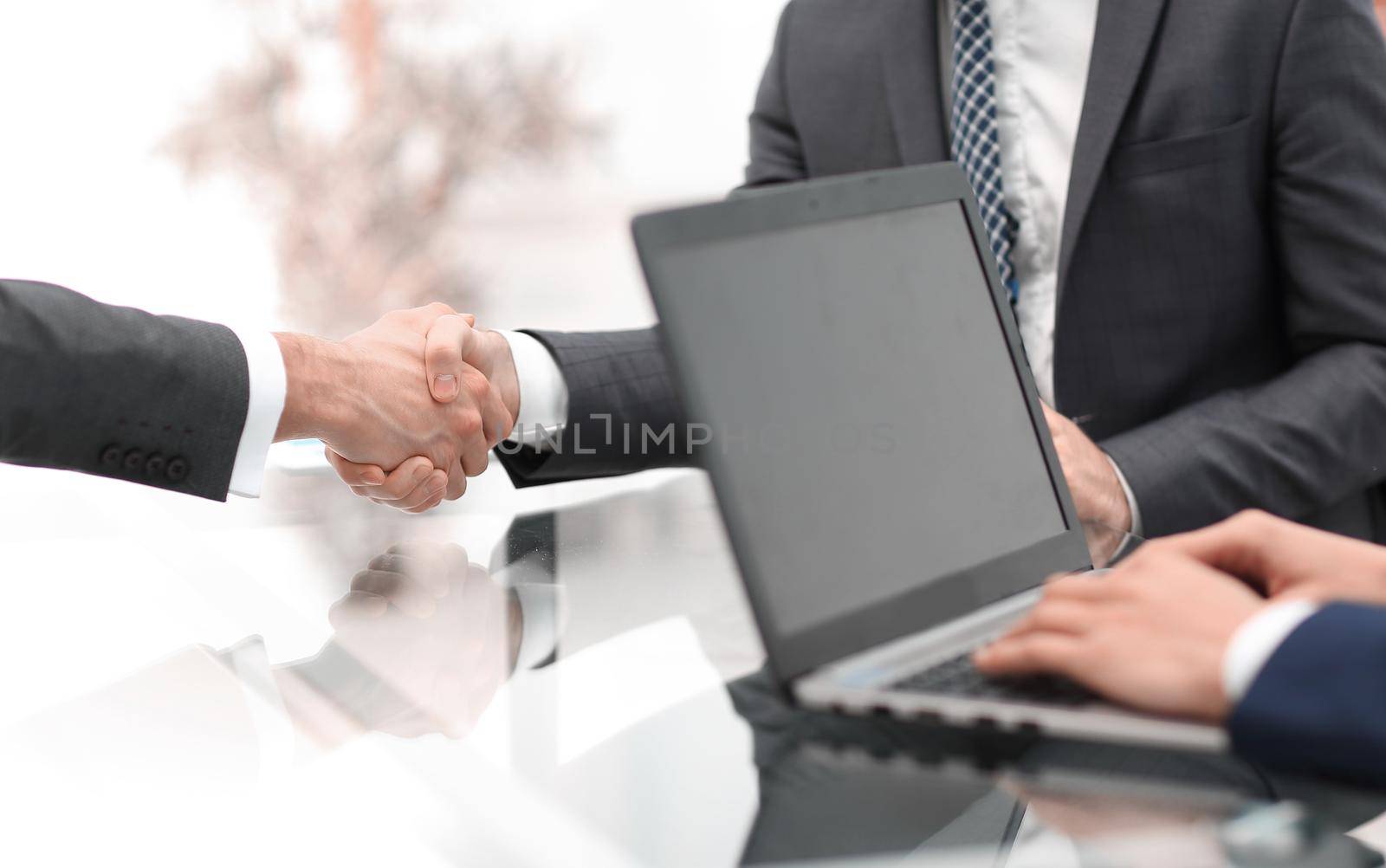 Two confident businessmen shaking hands during a meeting in the by asdf