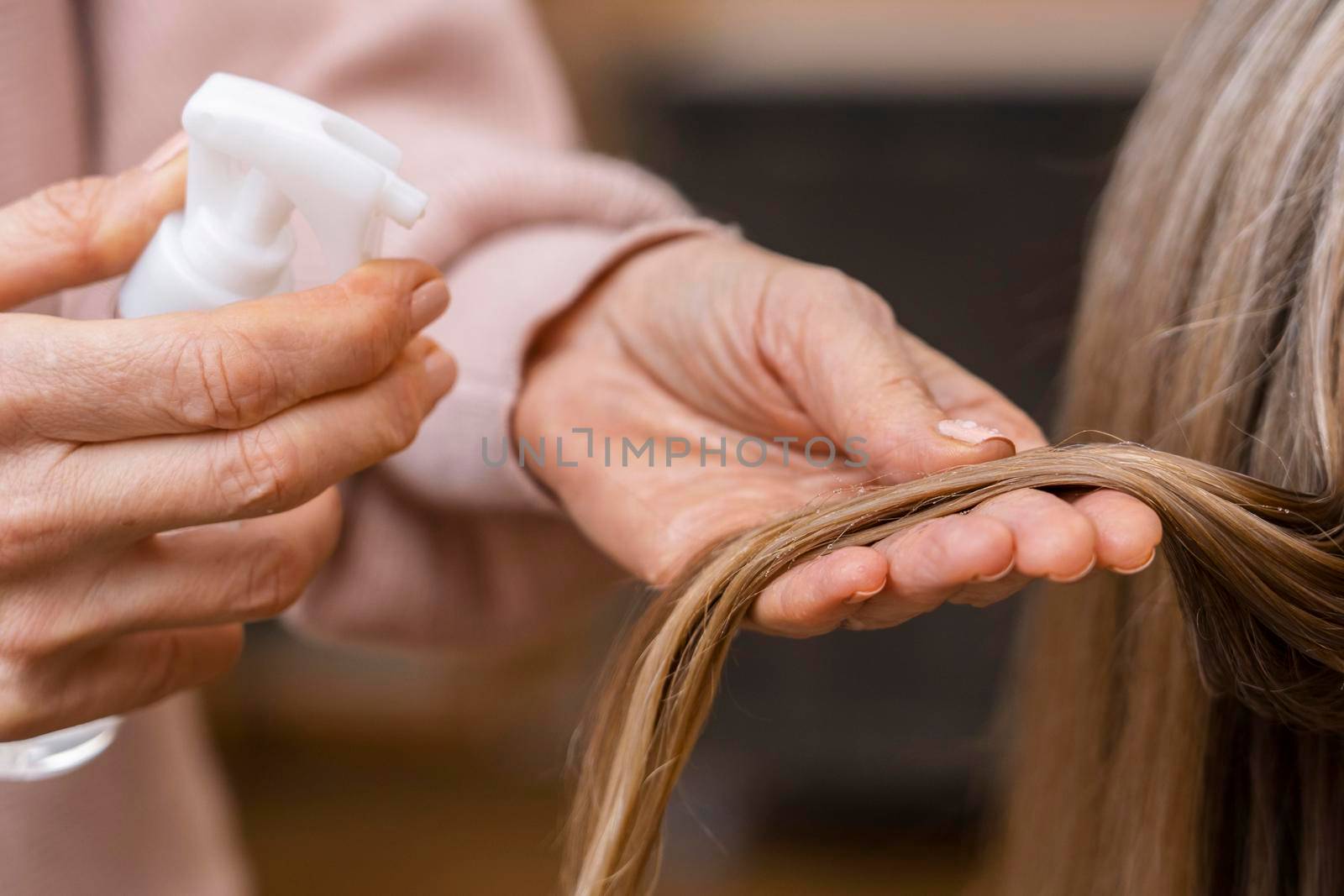 hairdresser holding tuft hair spraying with water by Zahard