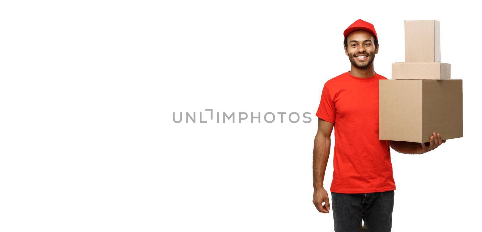 Delivery Concept - Portrait of Happy African American delivery man in red cloth holding a box package. Isolated on white studio Background. Copy Space by Benzoix