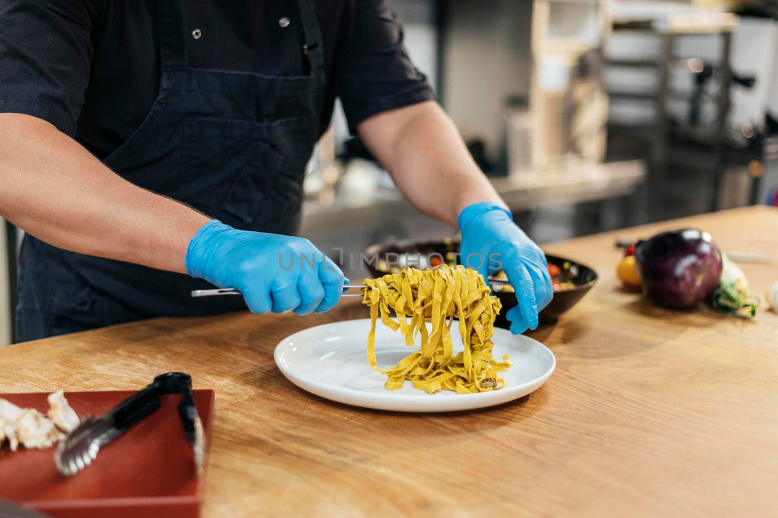 male chef with gloves putting pasta plate by Zahard