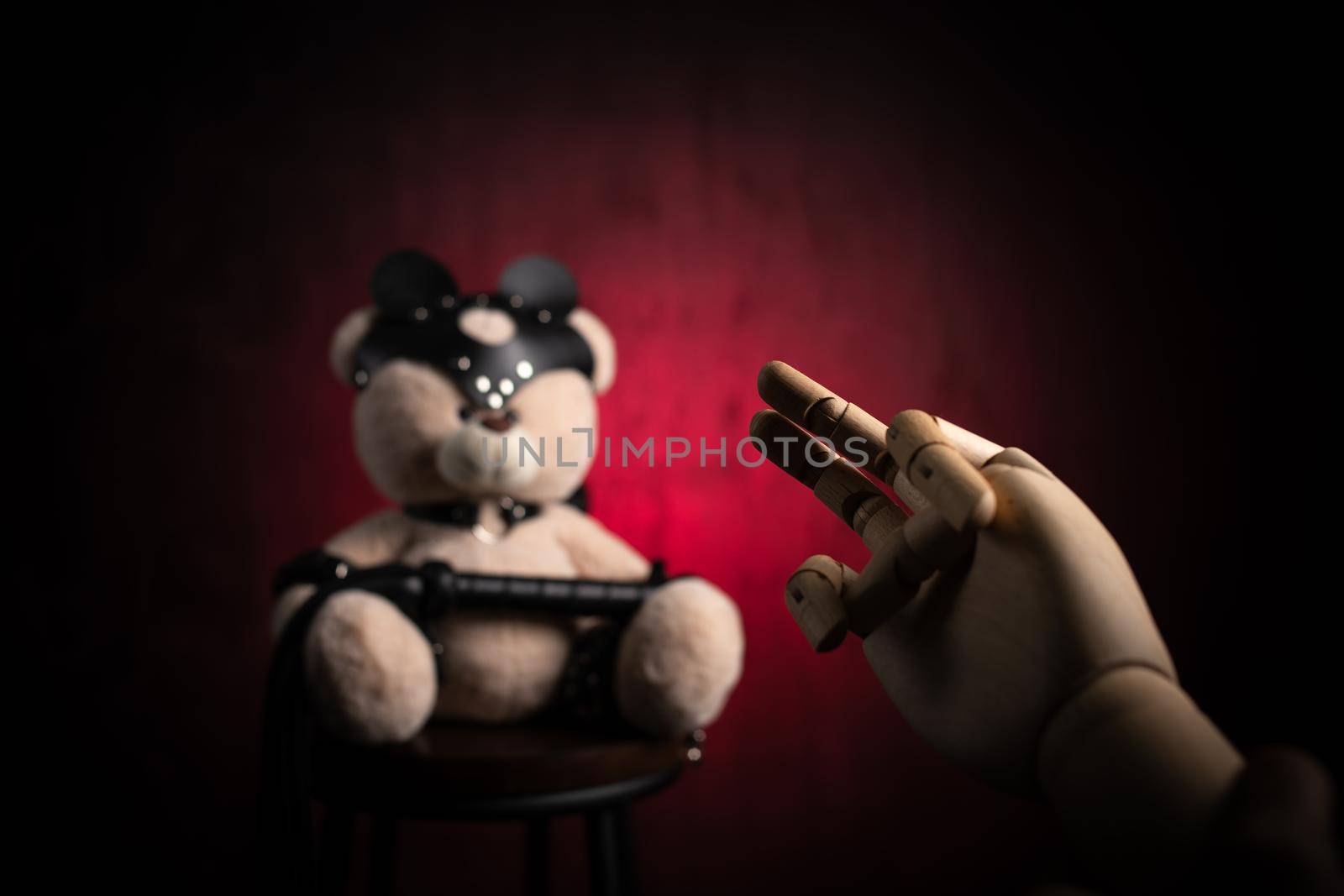 a toy teddy bear with a whip, dressed in leather belts and a mask, an accessory for BDSM games with a wooden hand and a sexual gesture by Rotozey