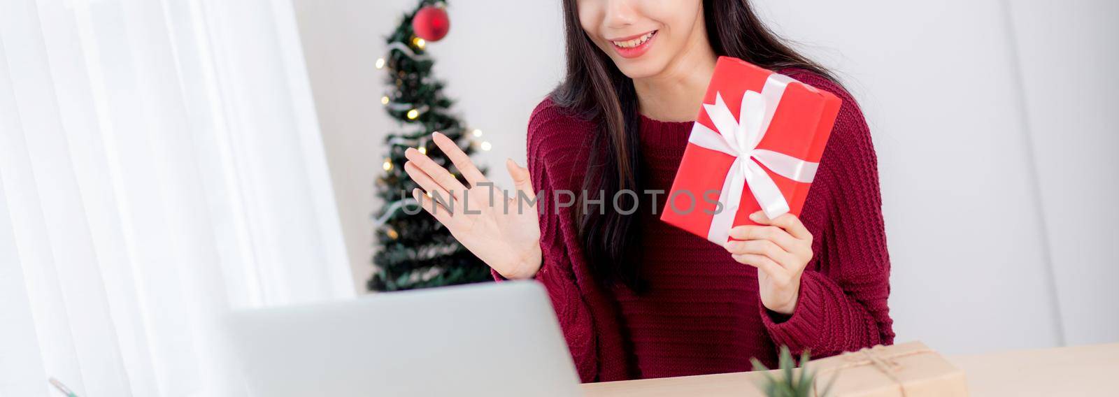 Young asian woman selfie video call online with friends and show gift box in Christmas day on phone at home, social distancing, new normal, female video conference, communication and holiday concept. by nnudoo