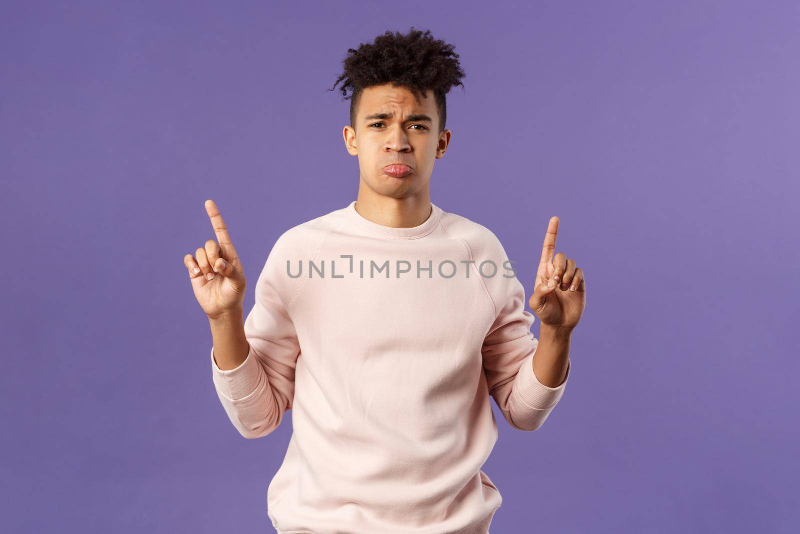 Portrait of gloomy, pouting frowning hipster guy dont have something he wants, pointing fingers up at super cool expensive thing, asking for it, trying receive compassion, purple background by Benzoix