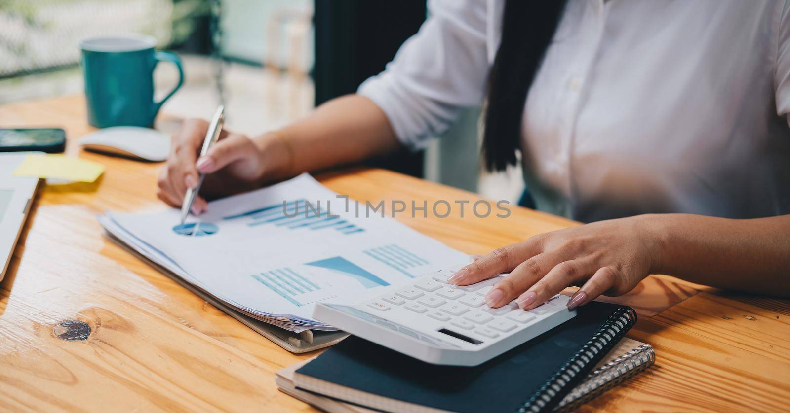 Business woman using calculator for do math finance on wooden desk in office and business working background, tax, accounting, statistics and analytic research concept