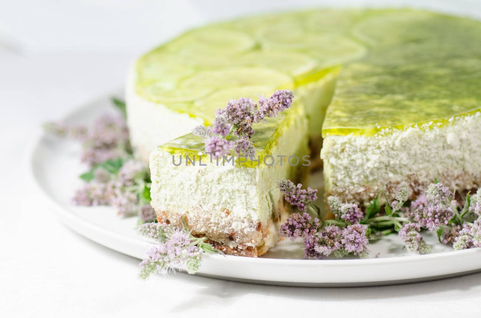 Lime cheesecake decorated with mint flowers, blurred background. From series "Summer desserts"