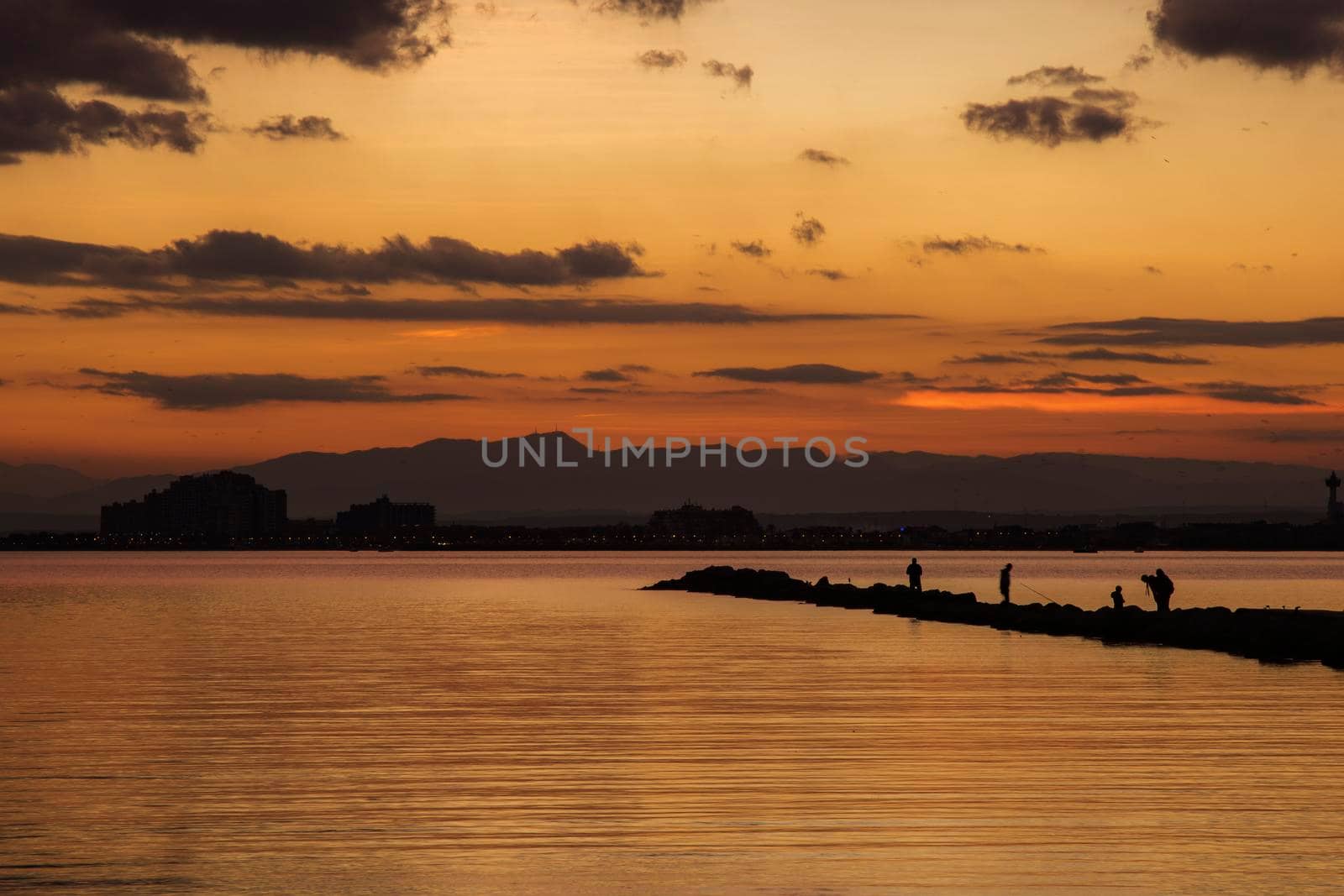 Sunset view of Roses beach in Costa Brava in Catalonia, showing some people silhouettes