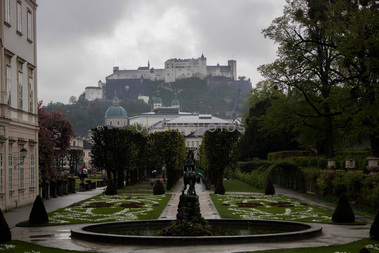 Mirabell Palace and gardens perspective and a castle in the background under a stormy sky in Salzburg