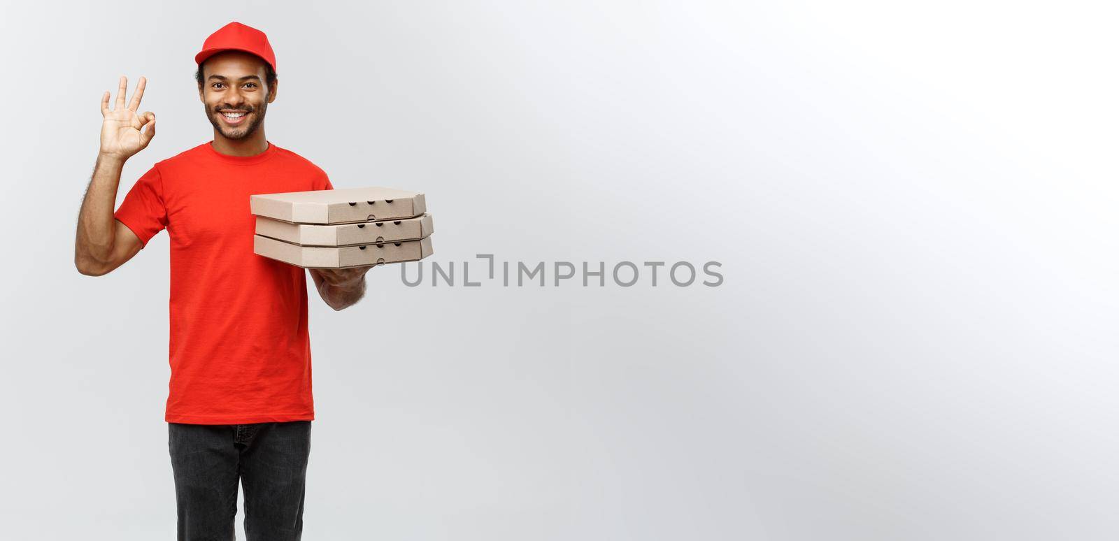 Delivery Concept - Portrait of Handsome African American Pizza delivery man making ok sign with fingers. Isolated on Grey studio Background. Copy Space. by Benzoix
