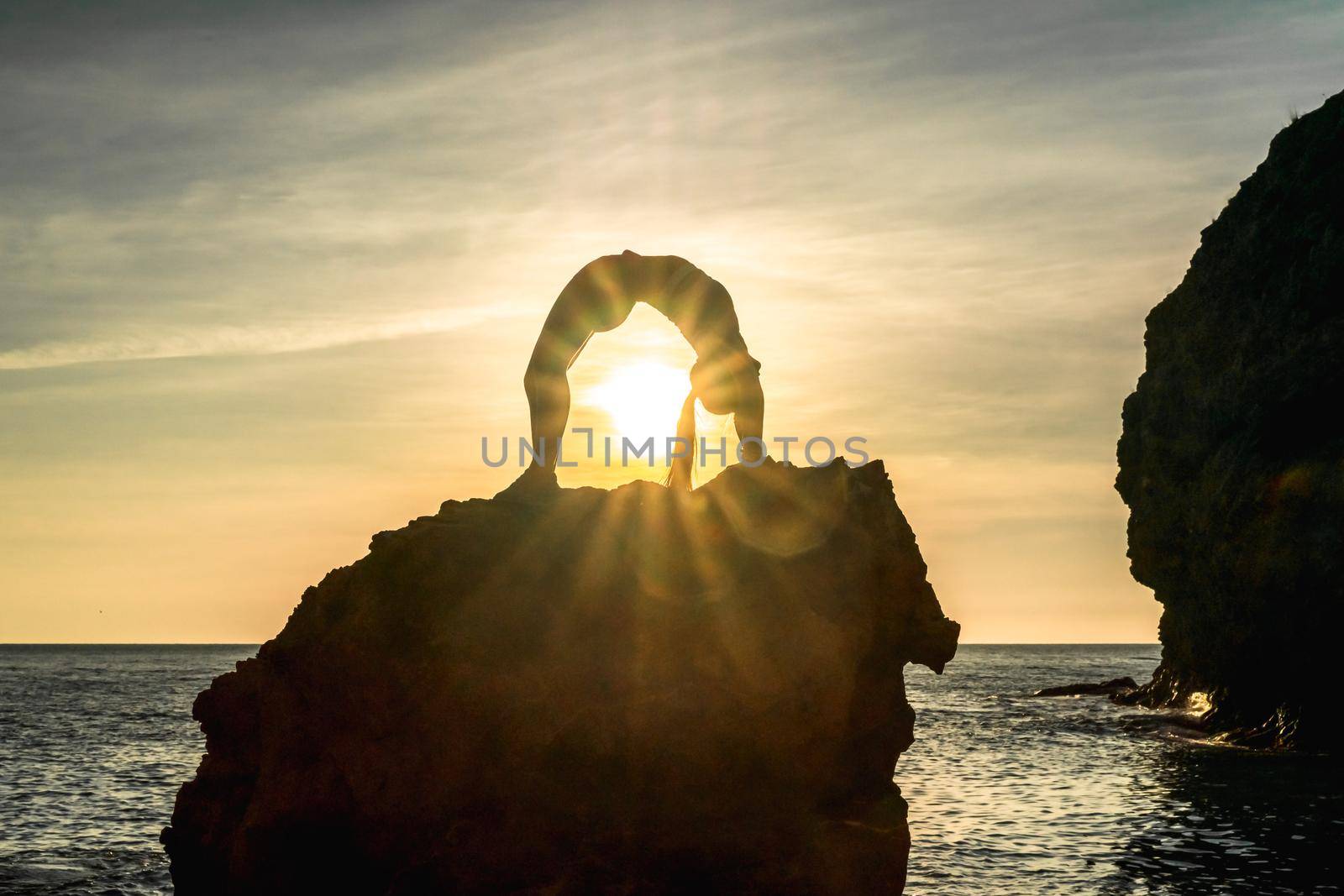 Girl gymnast is training on the beach by the sea sunset. Does twine. Photo series. by Matiunina