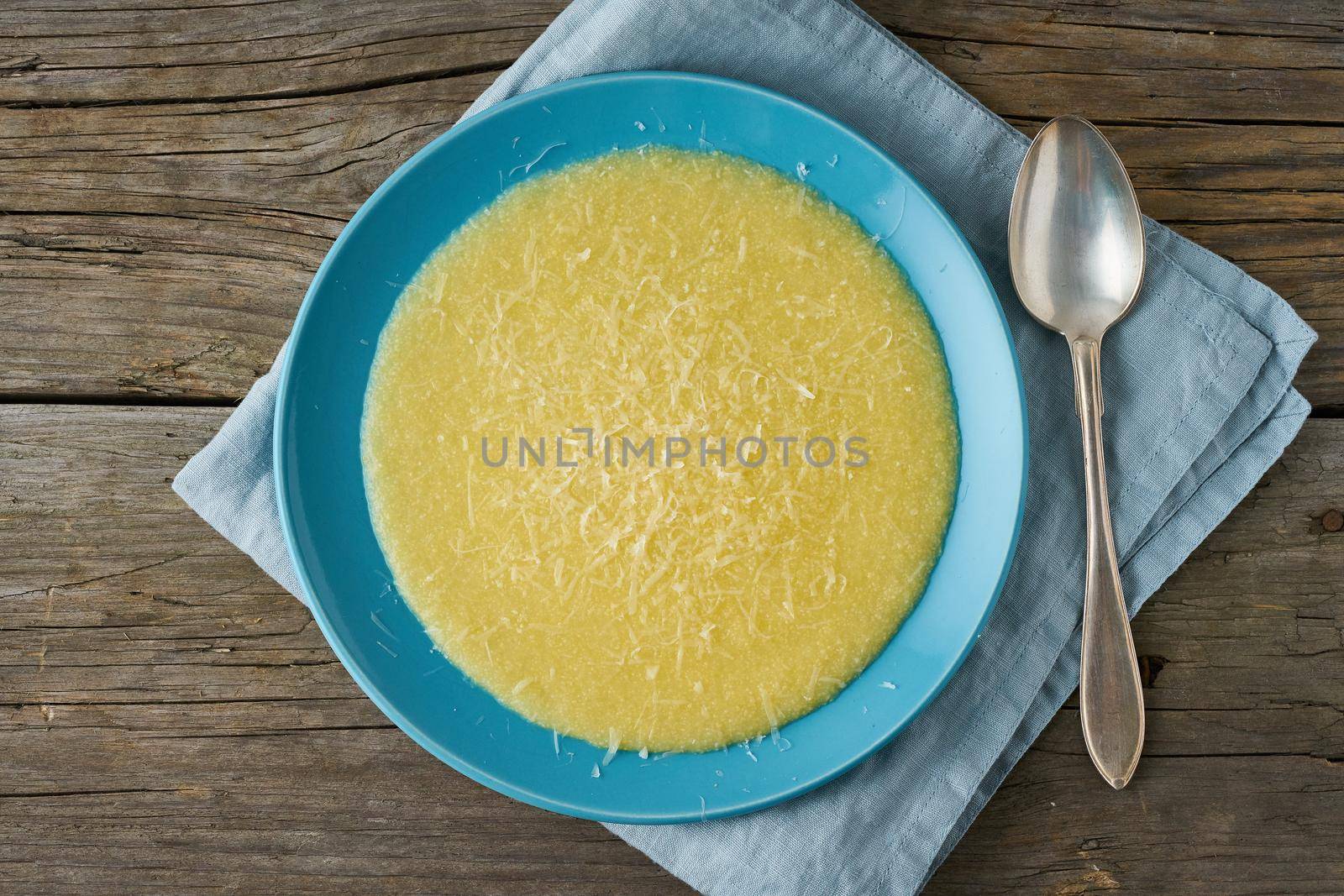 Polenta, porridge with Parmesan cheese on old dark wooden background, top view, traditional Italian cuisine