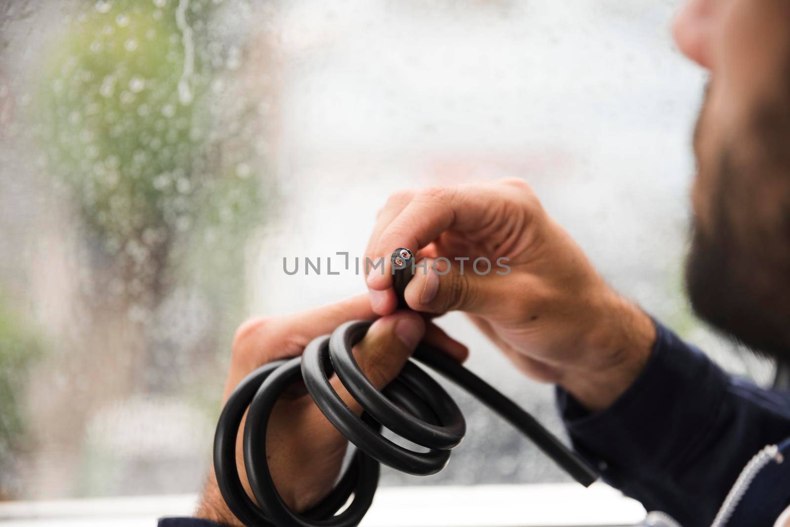 close up electrician s hand holding black electric cable by Zahard