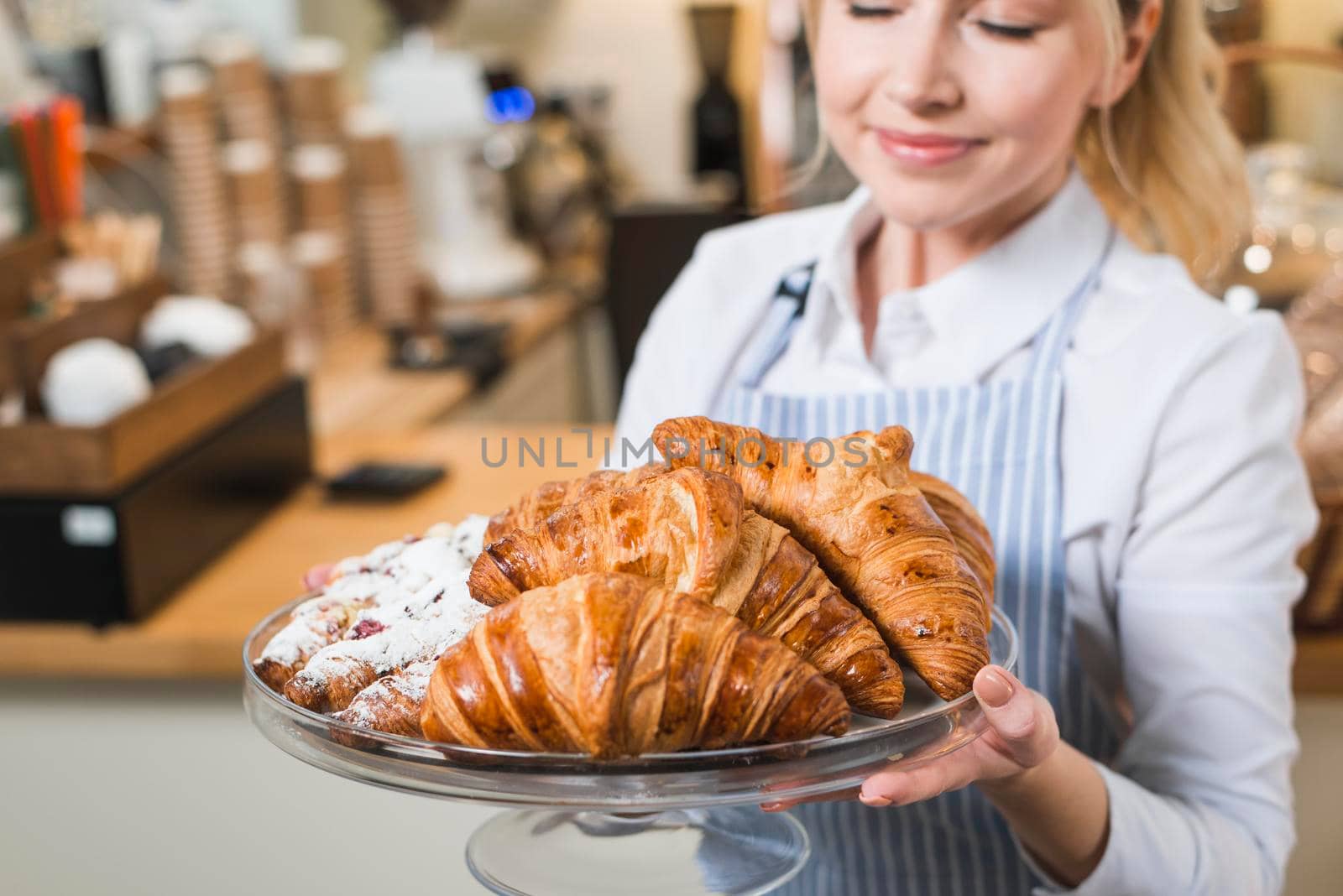close up smiling young woman smelling fresh baked croissants cake stand by Zahard