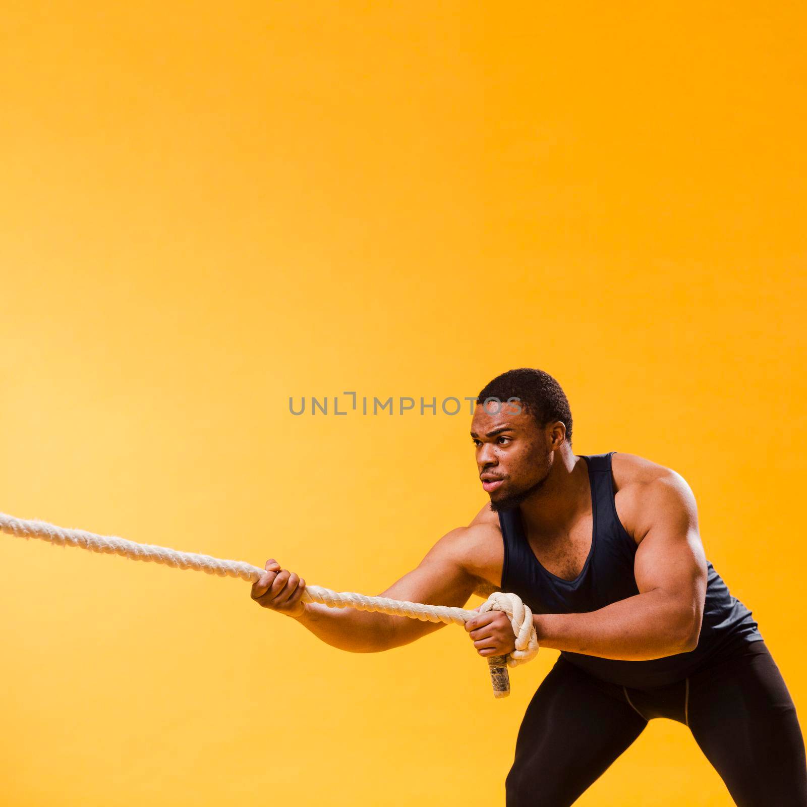 athletic man gym outfit pulling rope with copy space by Zahard