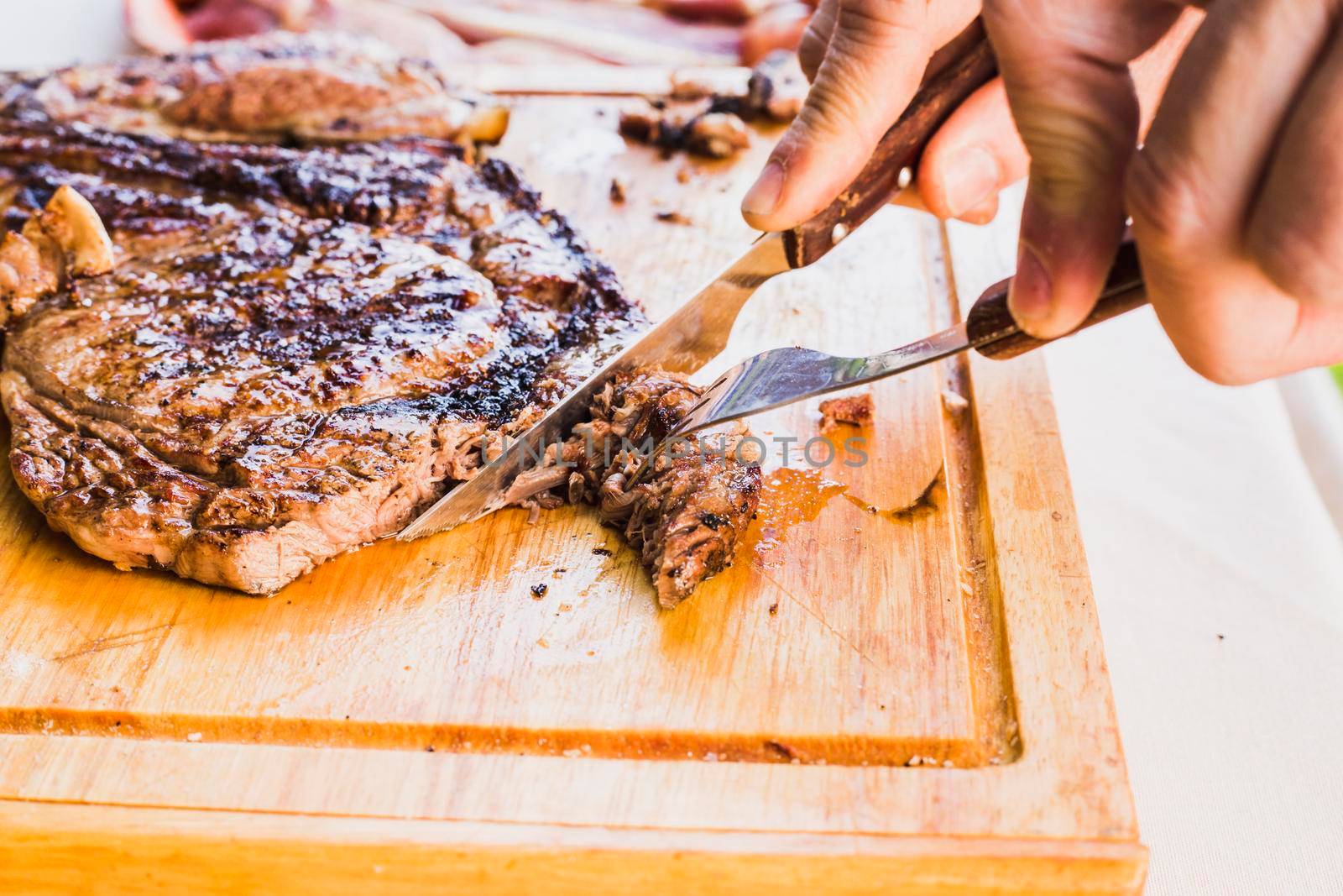 close up person s hand slicing meat with fork knife by Zahard