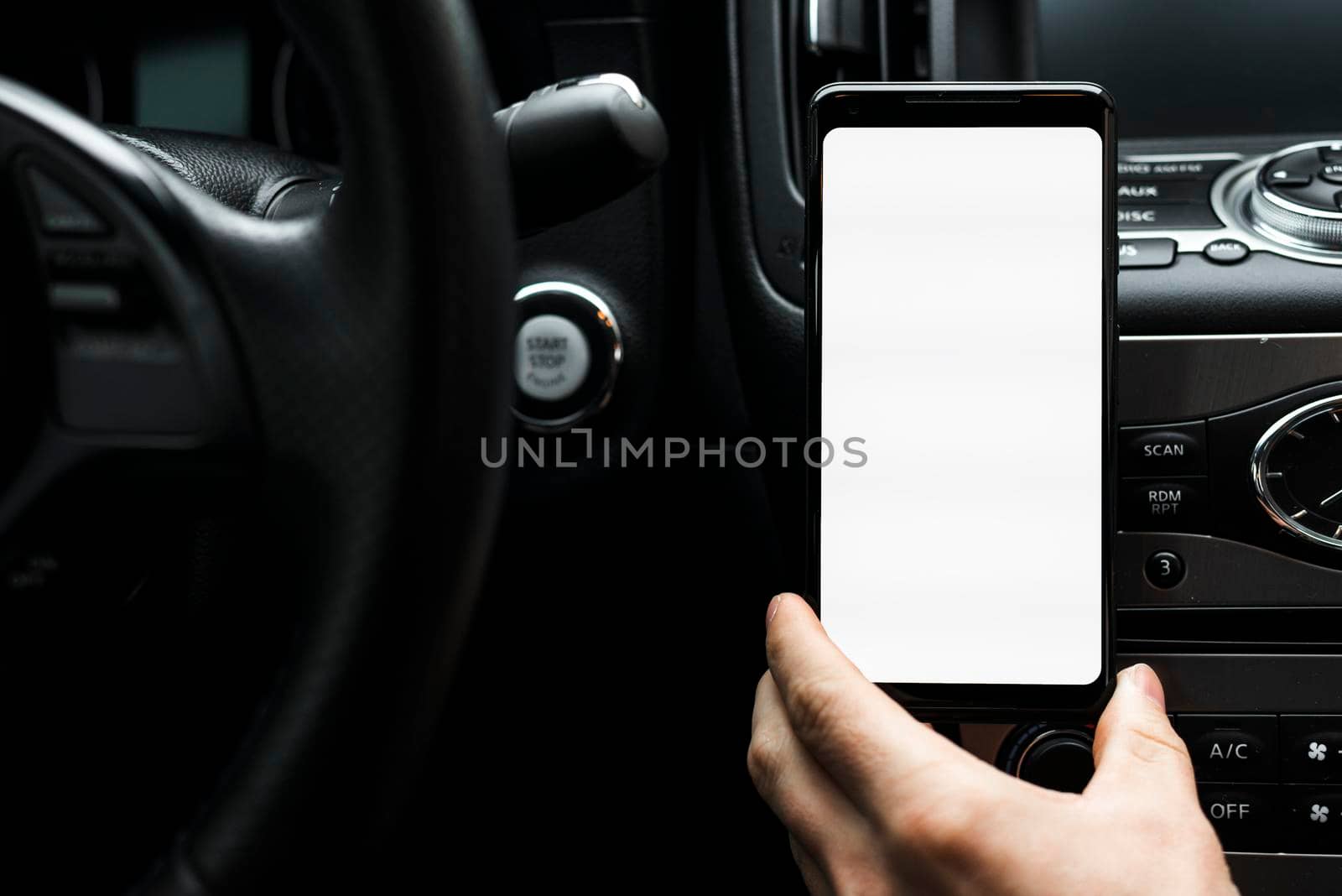 close up hand holding smart phone showing white blank screen car