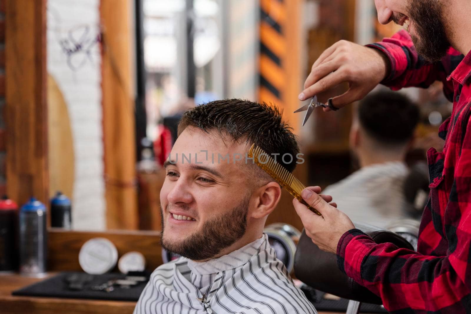 young man trimming with scissors comb