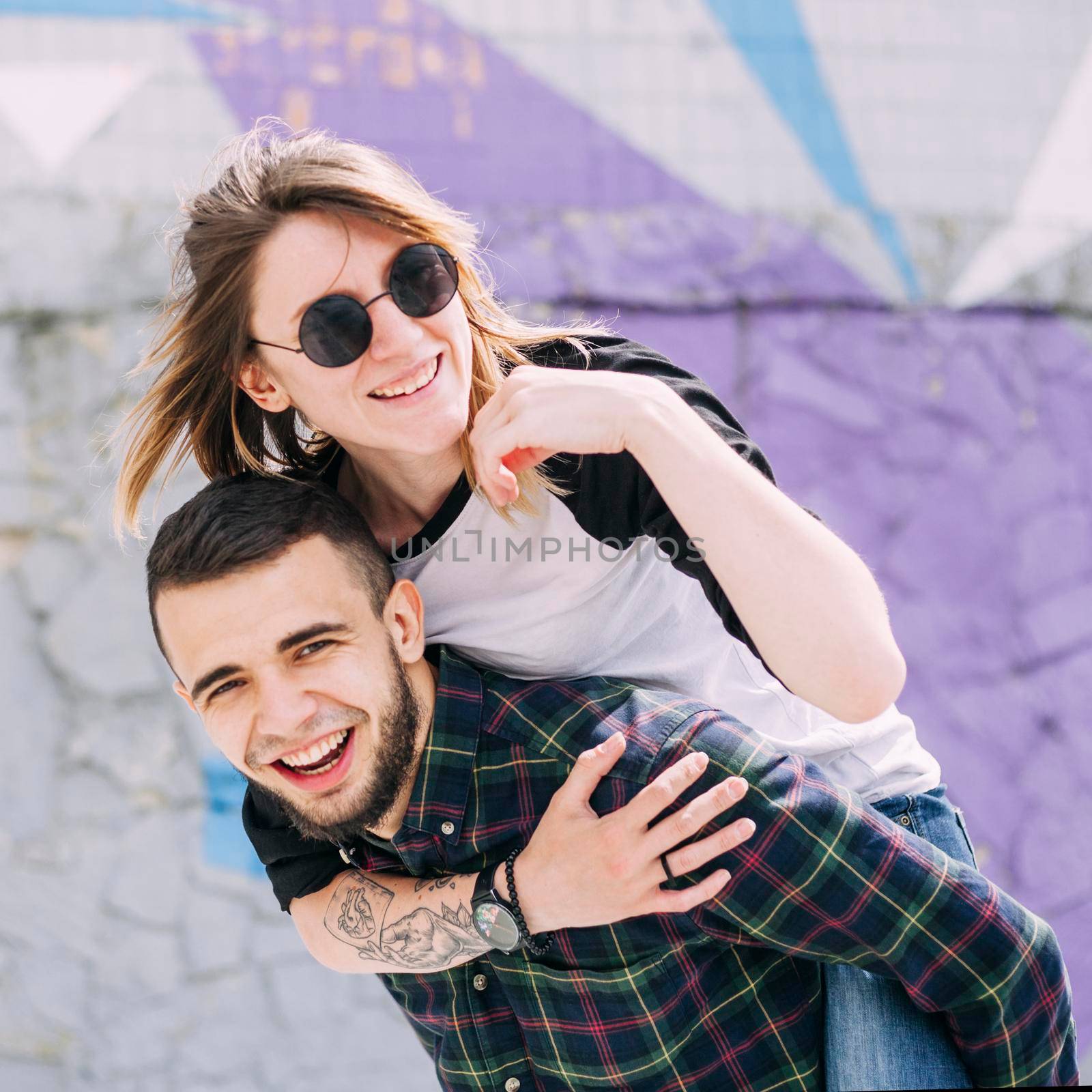 handsome smiling young man taking her piggy ride his back