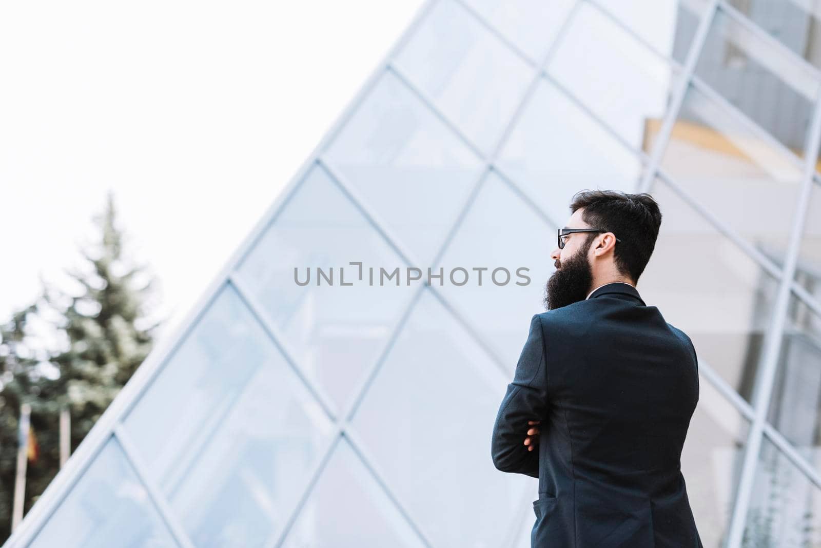 close up businessman standing front corporate building by Zahard