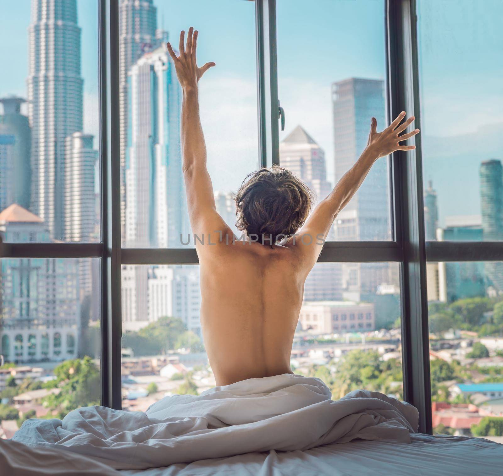 Man wakes up in the morning in an apartment in the downtown area with a view of the skyscrapers. Life in the noise of the big city concept. Not enough sleep by galitskaya