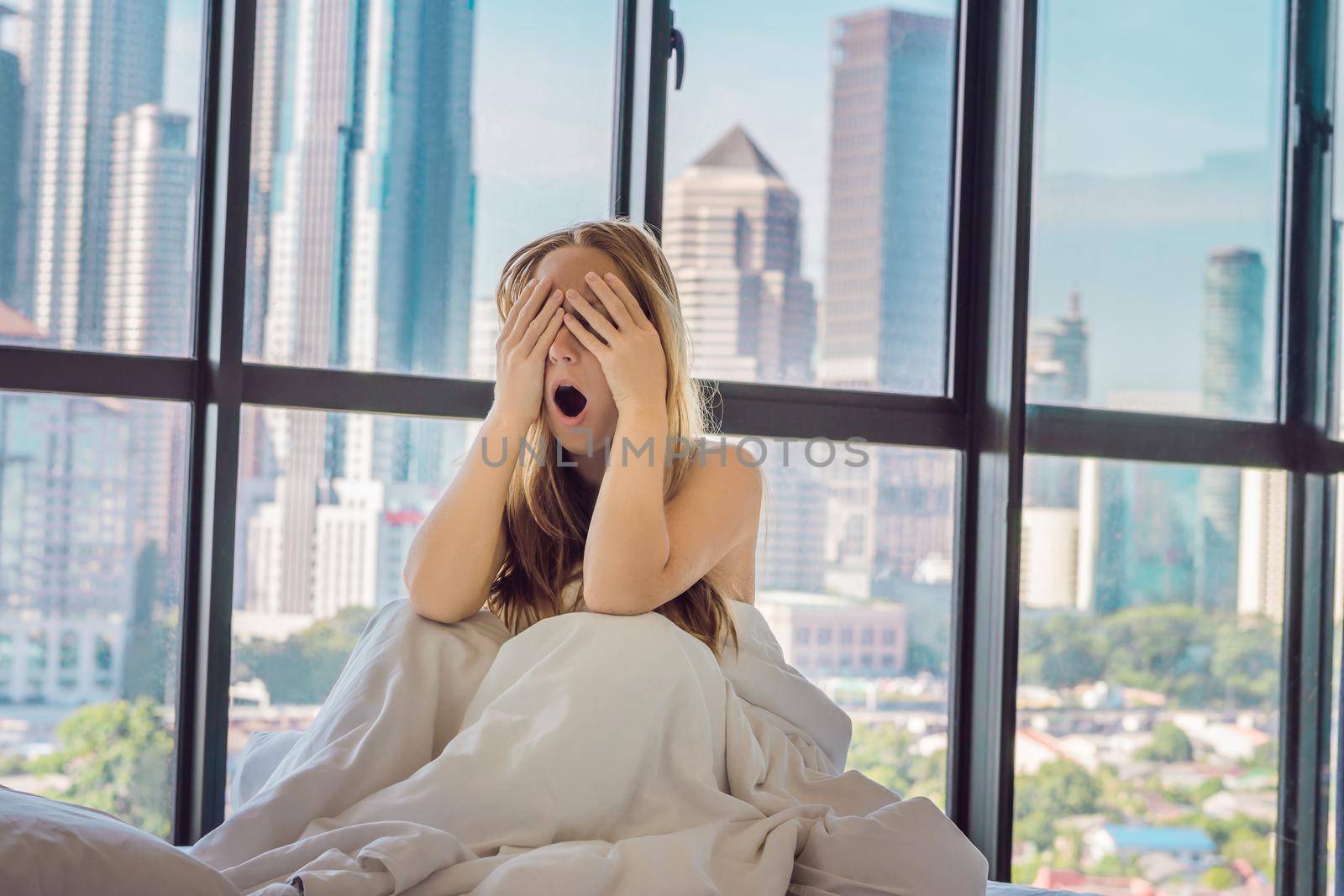 Woman wakes up in the morning in an apartment in the downtown area with a view of the skyscrapers. Life in the noise of the big city concept. Not enough sleep by galitskaya