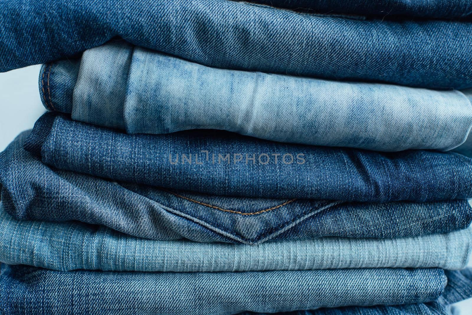 Stack of a stack of old jeans various shades of blue jeans. Denim jeans texture. Denim background texture for design. Canvas denim texture. by Smile19