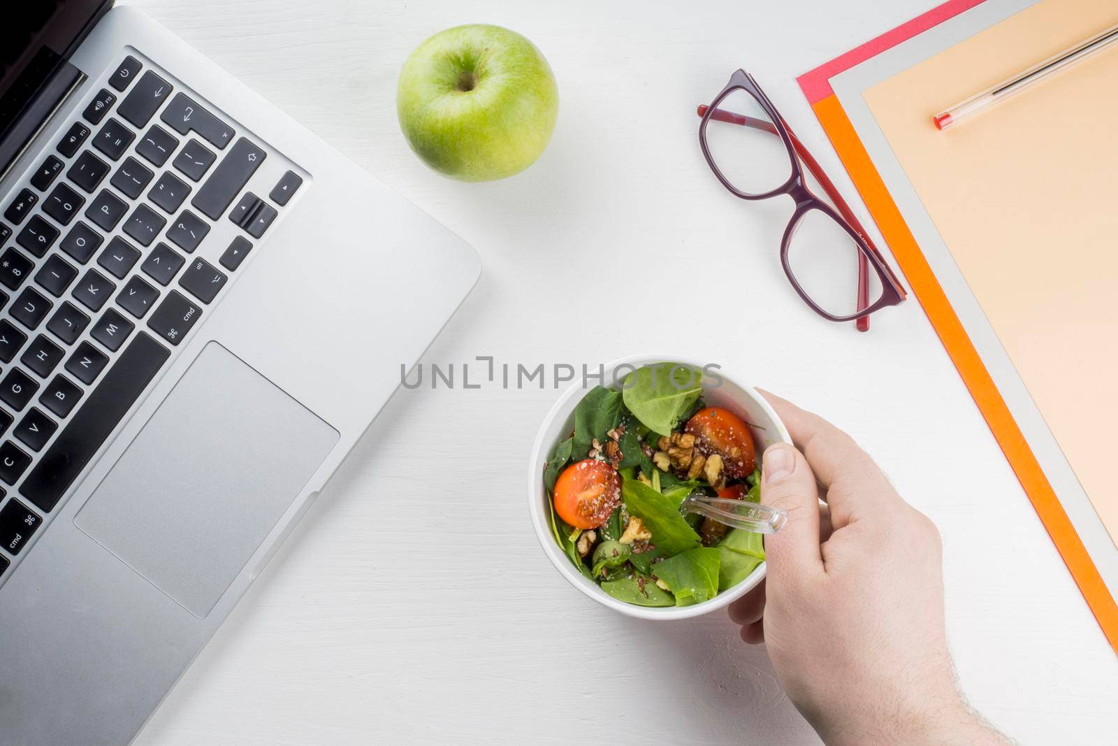 crop hand putting salad near laptop by Zahard