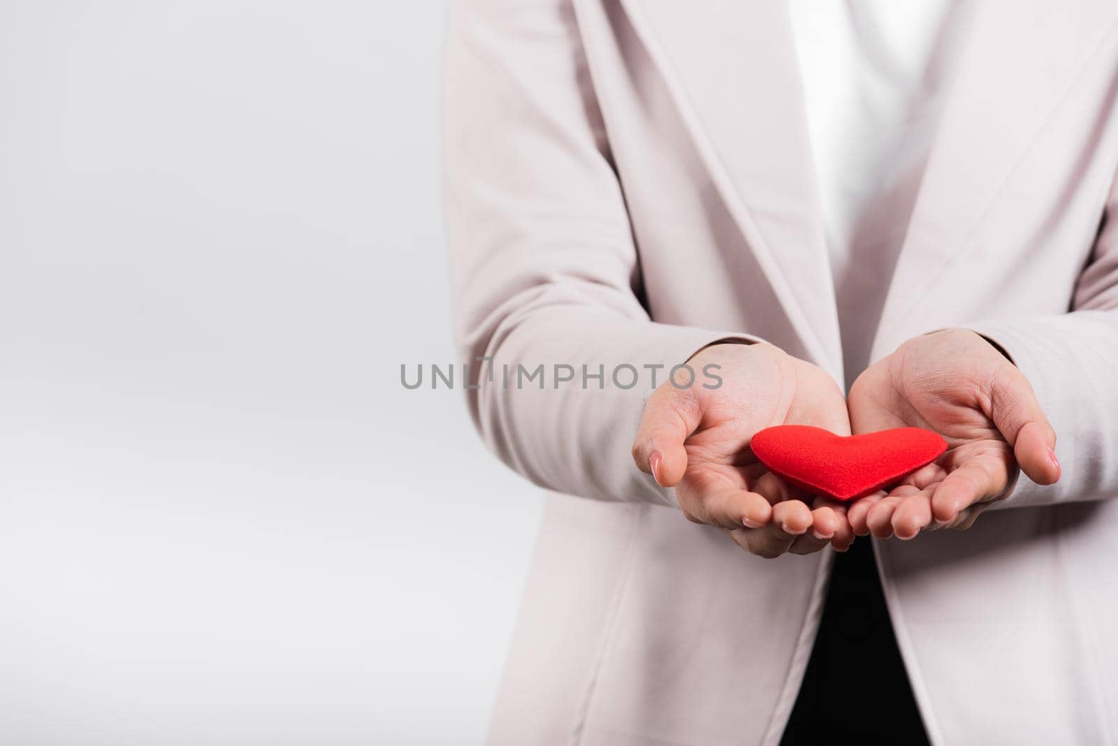 Smiling woman confidence showing holding red heart with her hand palm isolated white background by Sorapop