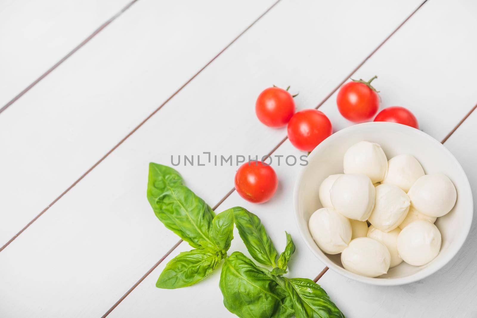 mozzarella cheese ball with basil leaf red tomatoes wooden white background by Zahard