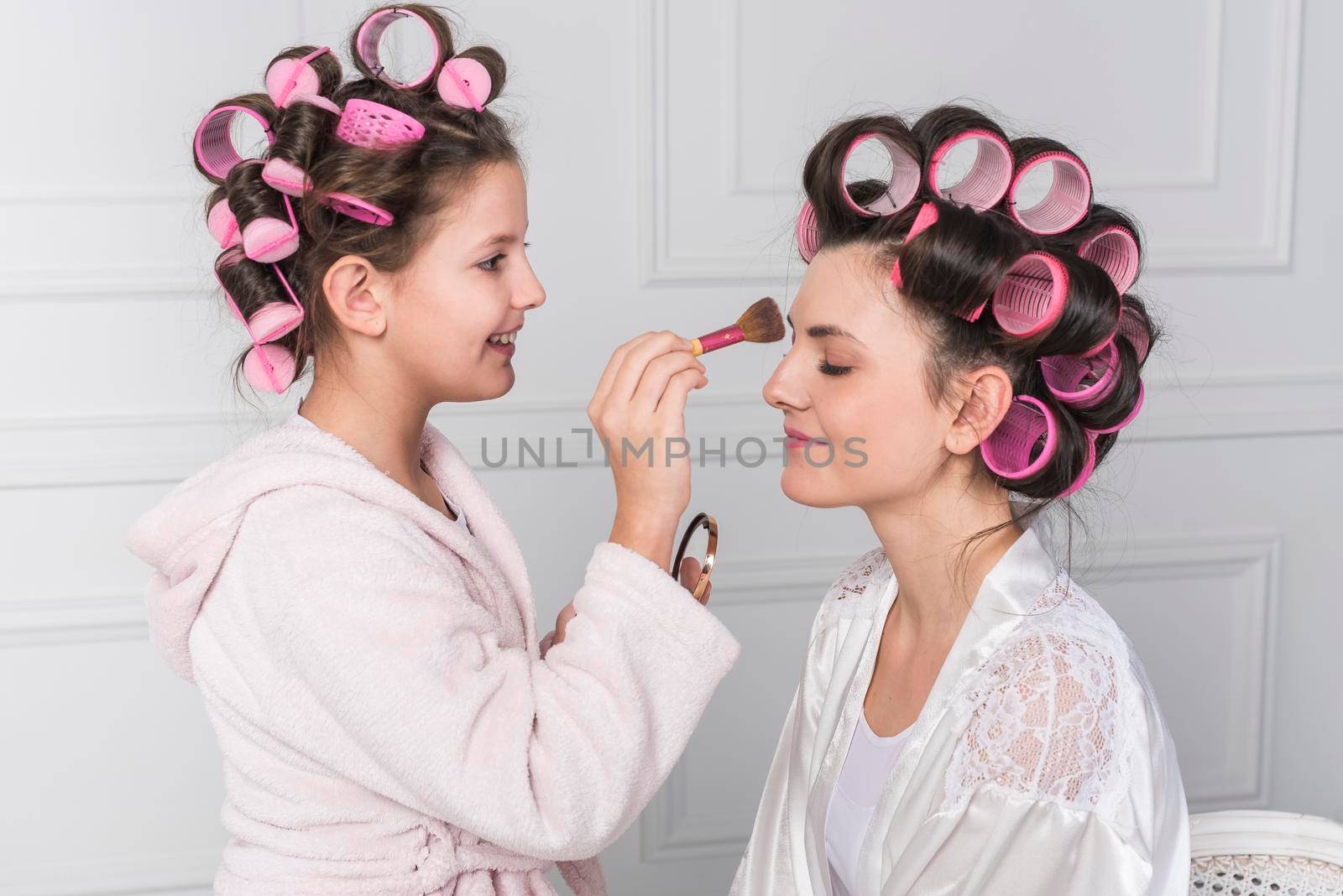 daughter putting powder mothers forehead