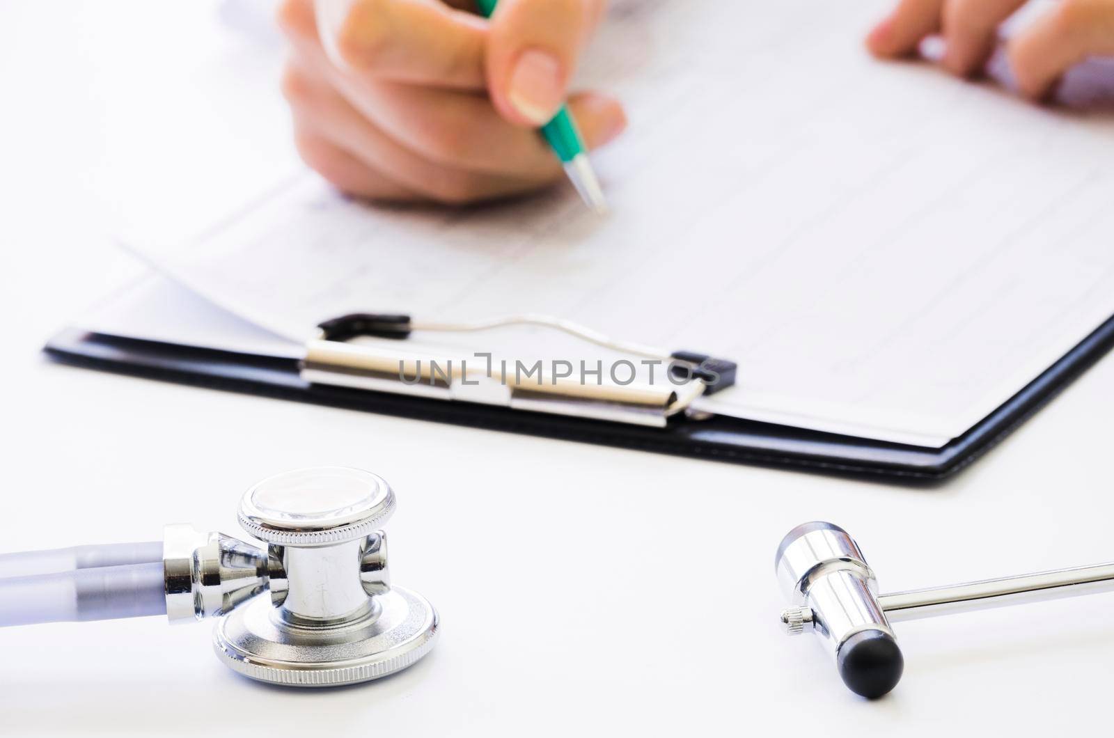 close up doctor s hand holding pen checking medical report clipboard by Zahard