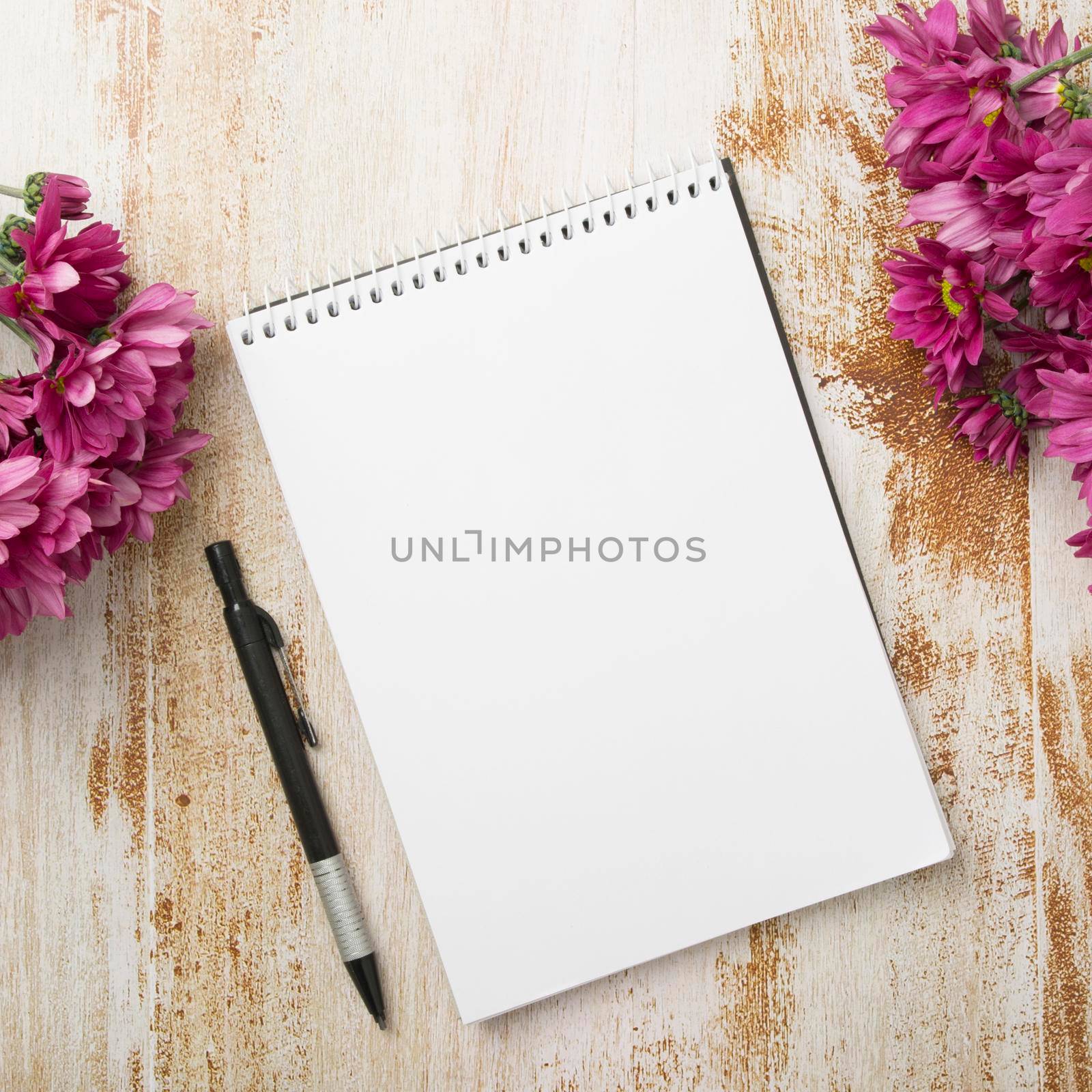 spiral notepad with pen pink flowers wooden textured background